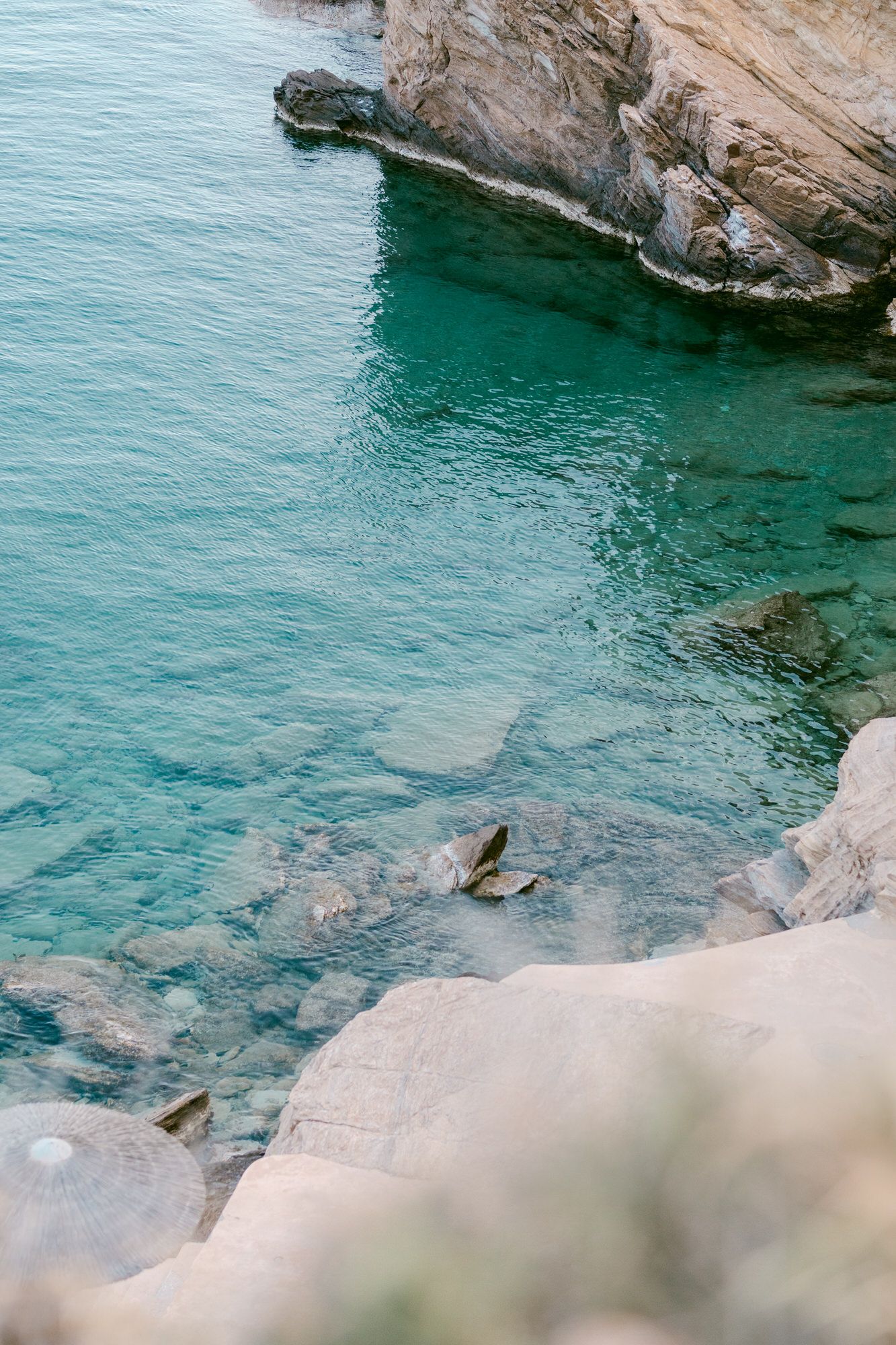 Crystal clear turquoise waters meet dramatic rocky cliffs along a pristine Mediterranean coastline.