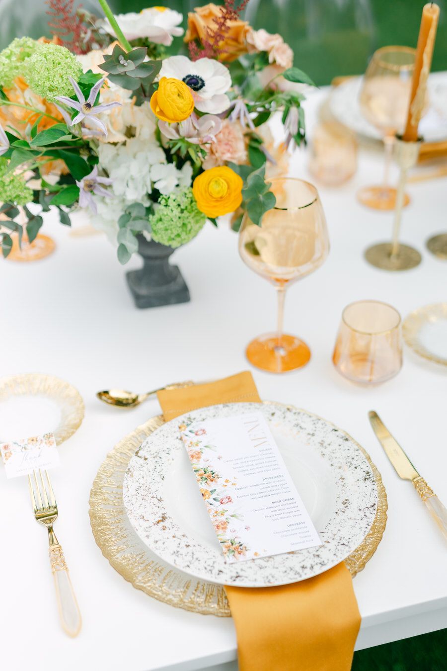 Elegant table setting with floral centerpiece and gold accents for wedding reception.