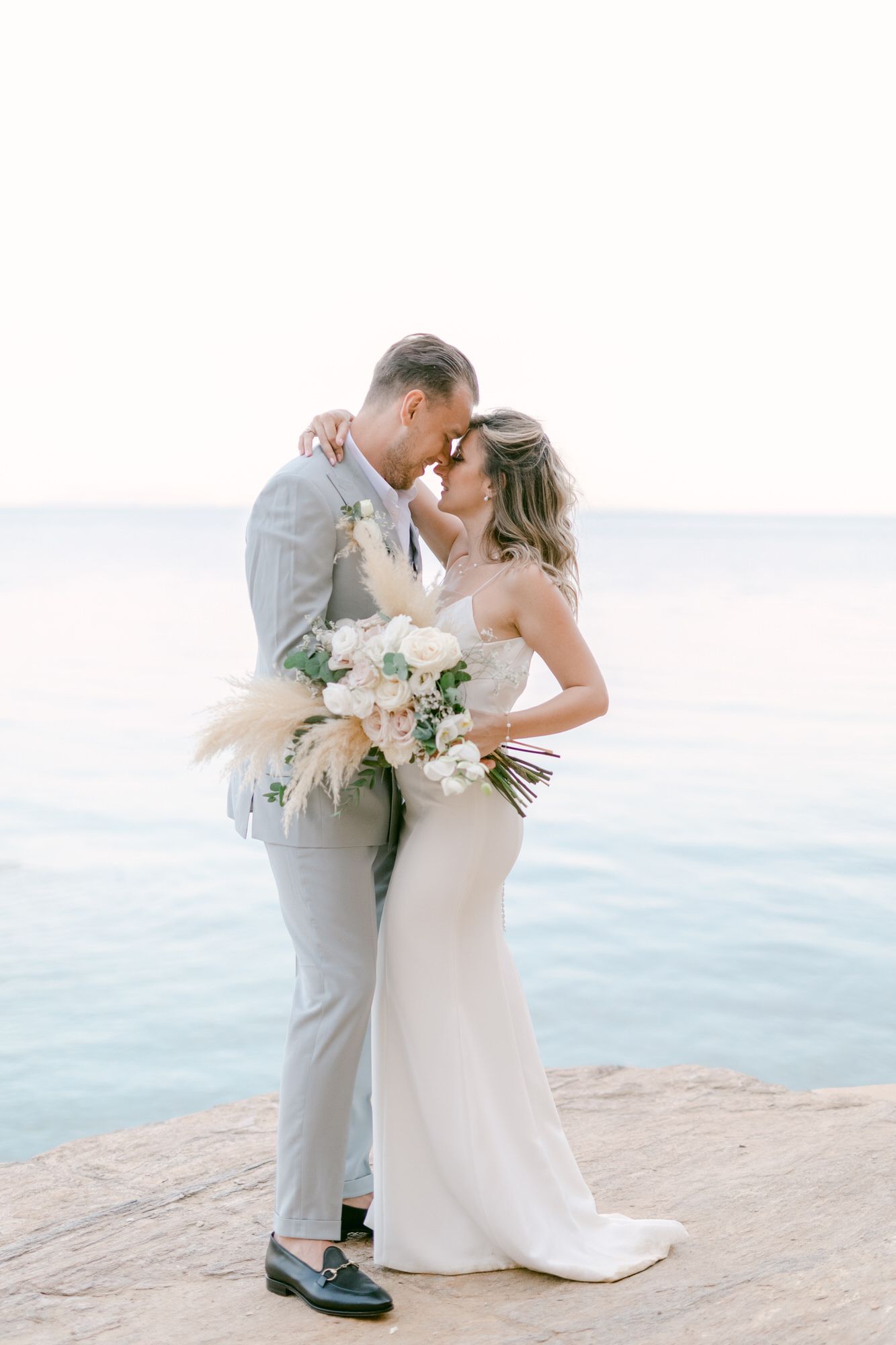 A romantic seaside portrait with a bouquet against an ocean backdrop.