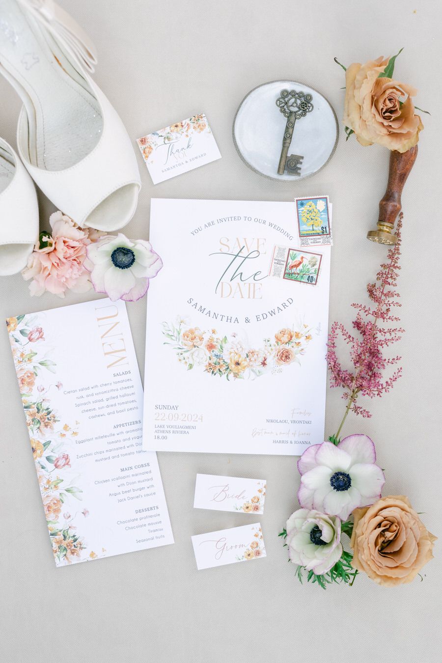Wedding invitation suite with floral design, vintage key, and peach roses on white background.