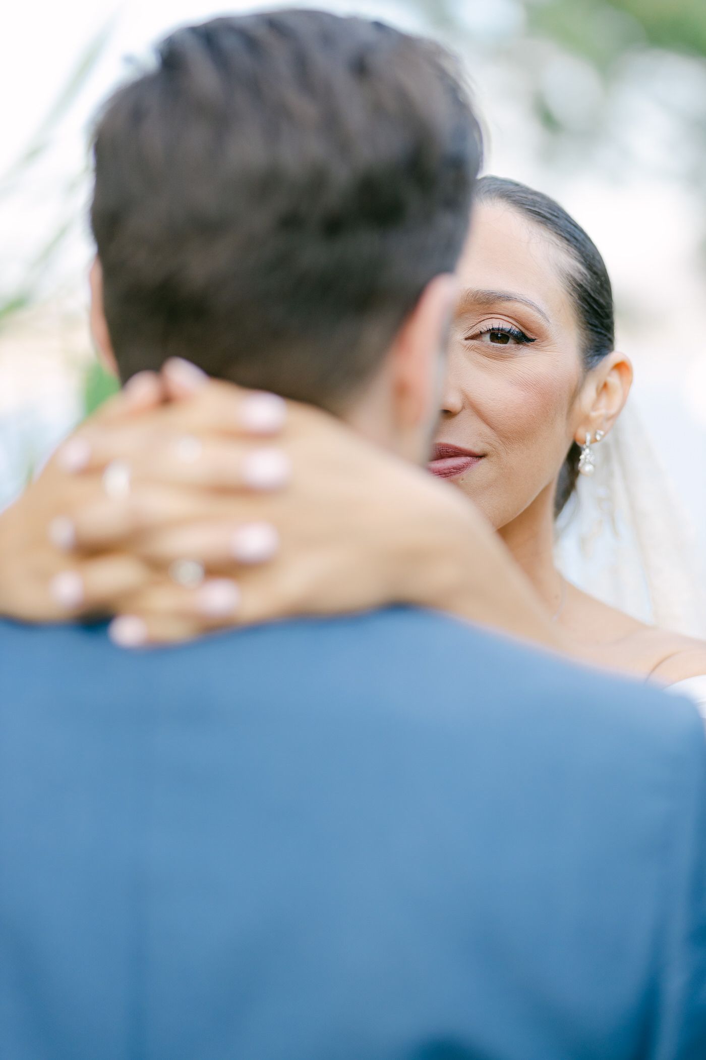 Bride smiles lovingly while embracing groom in intimate wedding moment during outdoor ceremony.