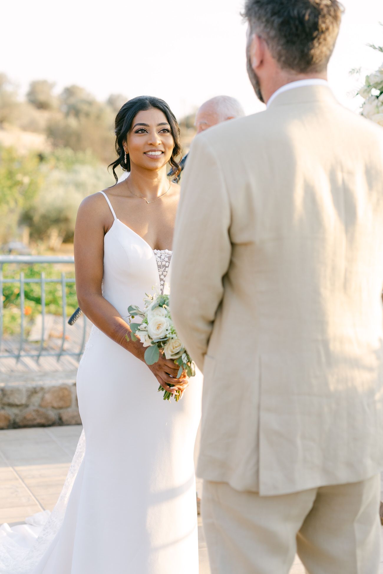 Bride in elegant white dress during outdoor wedding ceremony.