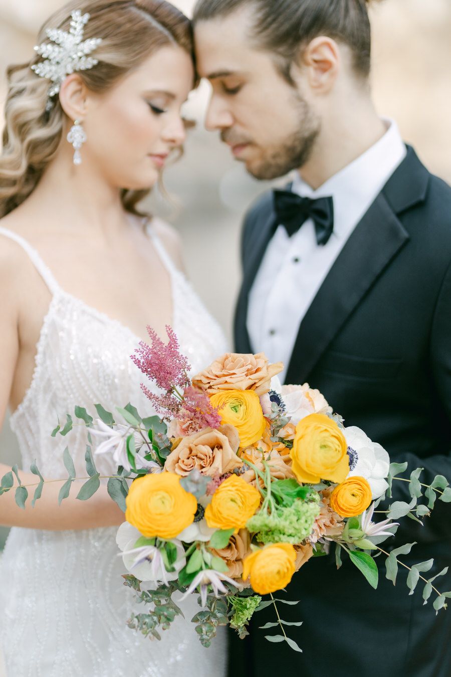 A tender moment captured with a vibrant yellow and orange bouquet.