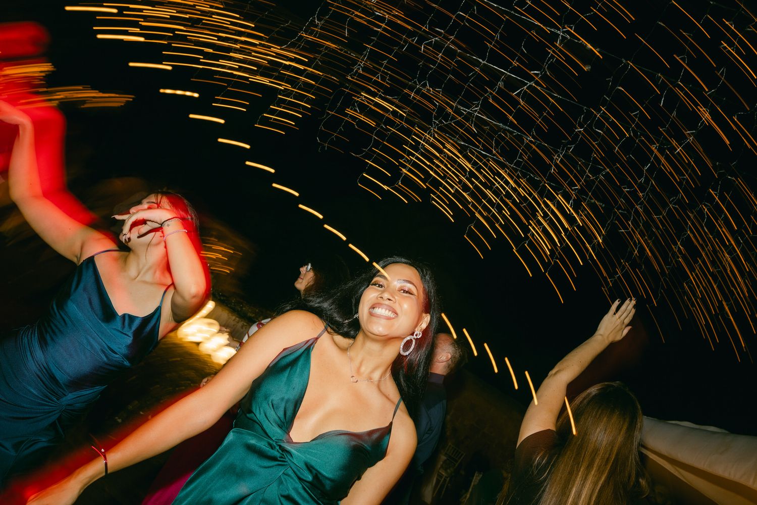People dancing energetically at a nightclub with blurred motion effects and curved ceiling architecture above.