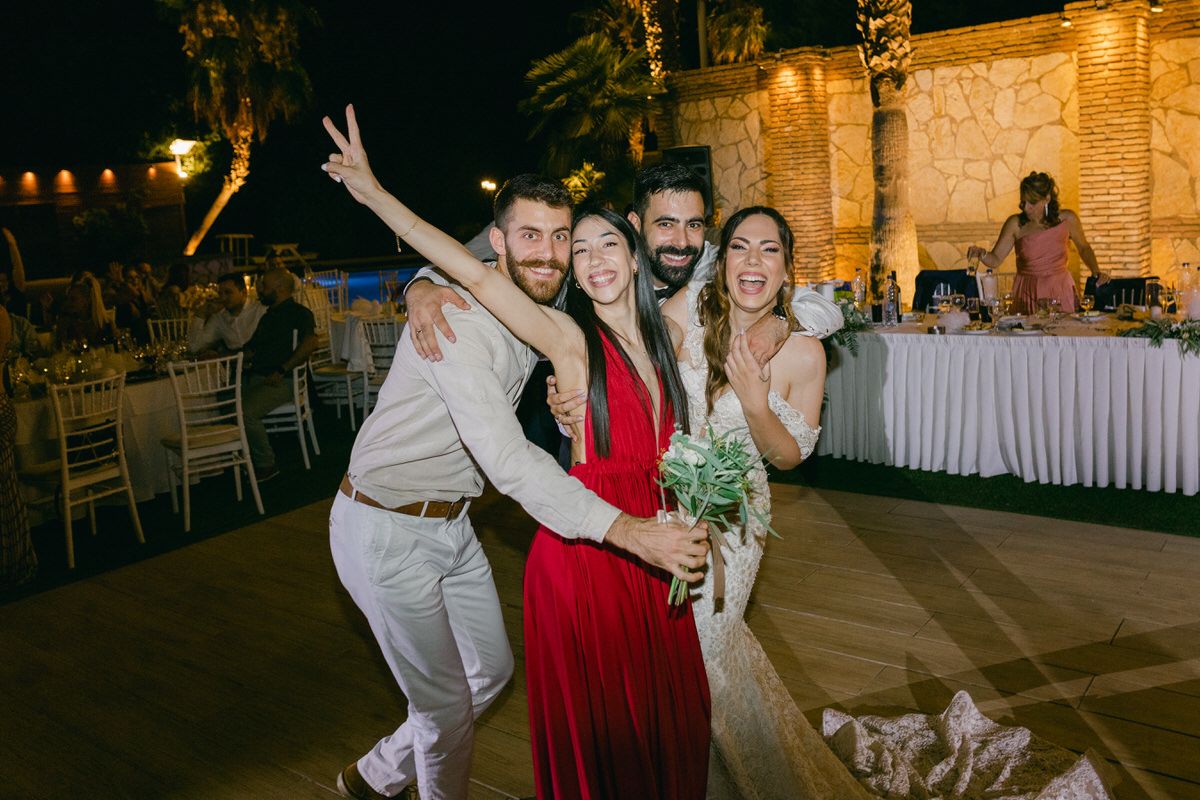 Wedding guests celebrate and pose together during an evening outdoor reception with string lights and decorated tables.