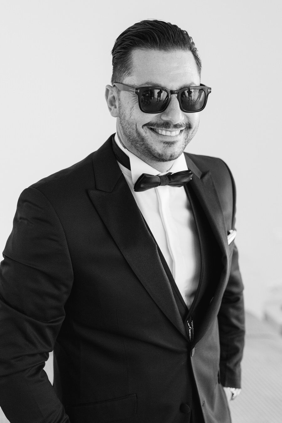 Classic black and white portrait of groom in tuxedo and sunglasses.