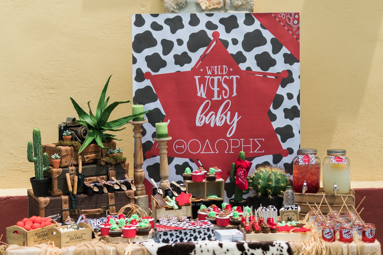 Western themed party table display cow print backdrop, cactus decorations and red accents for a baby celebration. Βαπτιση Tonia and Theodore