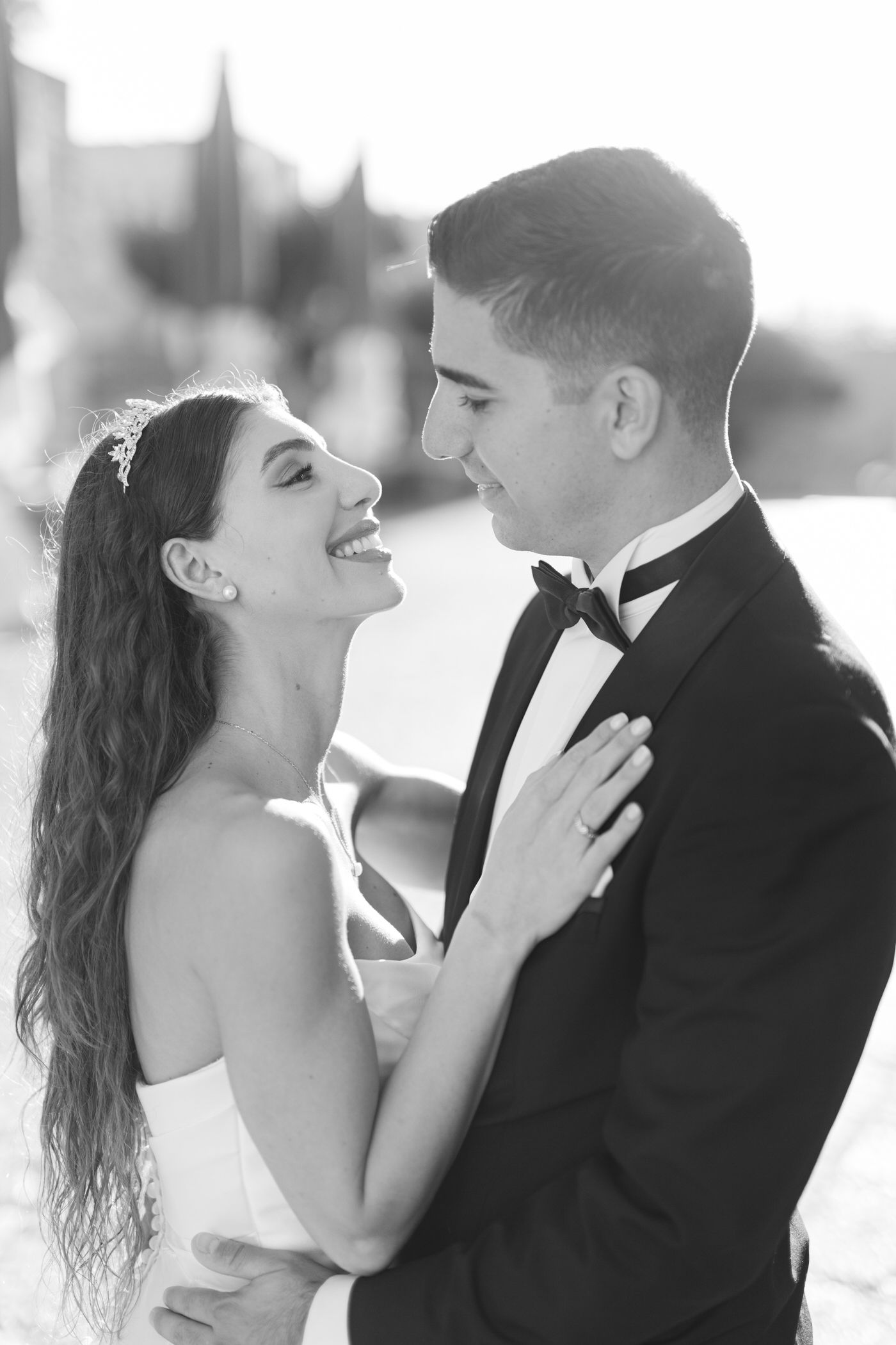 A romantic black and white wedding photo showing a joyful bride and groom sharing an intimate moment together outdoors.