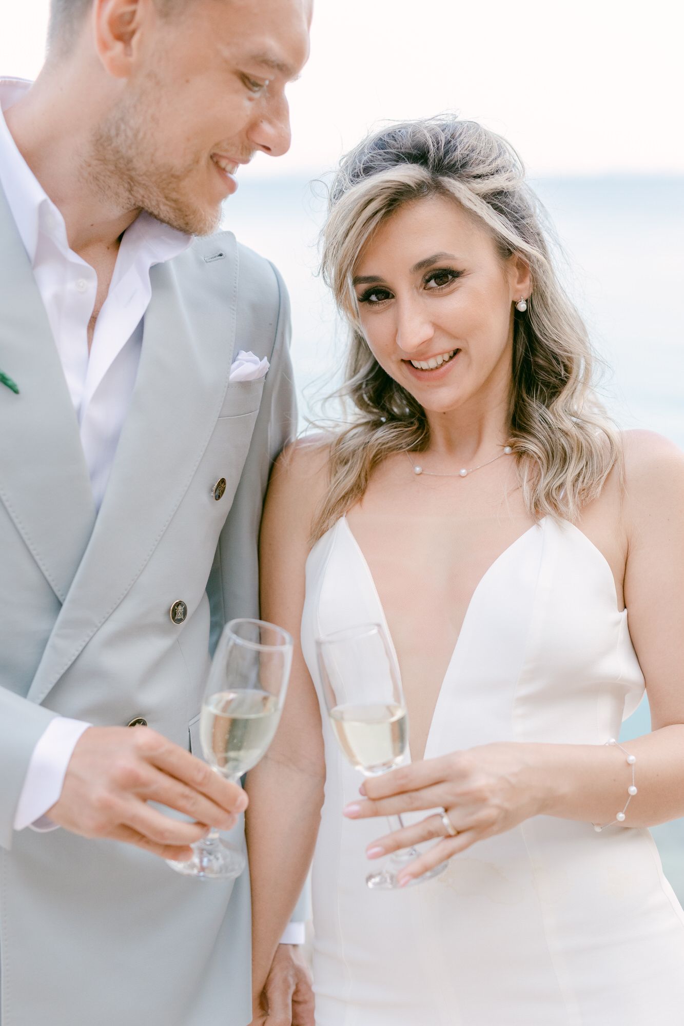 A celebratory moment with champagne glasses on a coastal setting.