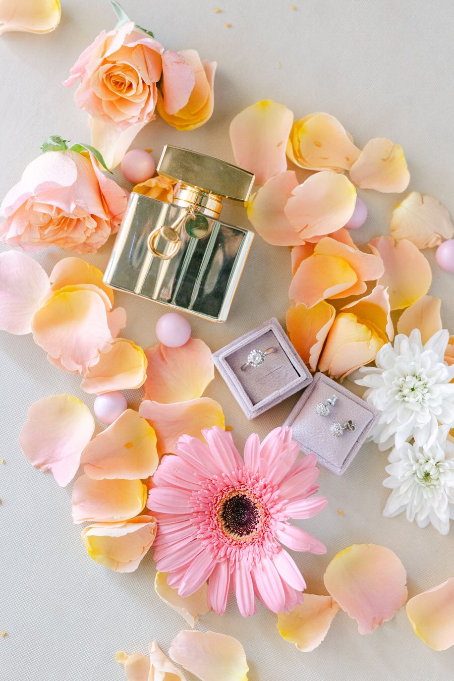Wedding rings and jewelry boxes arranged with pink roses and gerbera daisies.