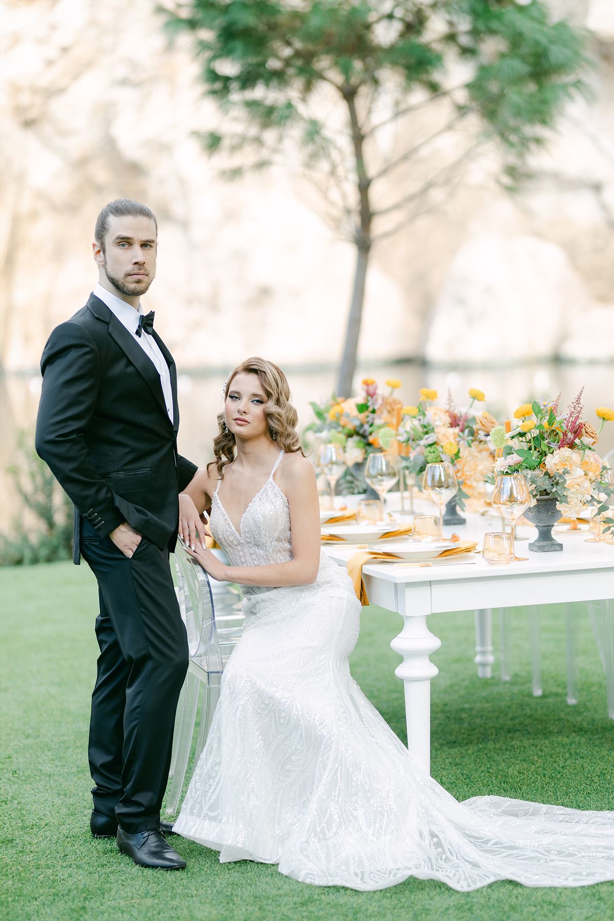 Beautiful outdoor wedding ceremony under a wooden pergola decorated with yellow and blue floral arrangements.