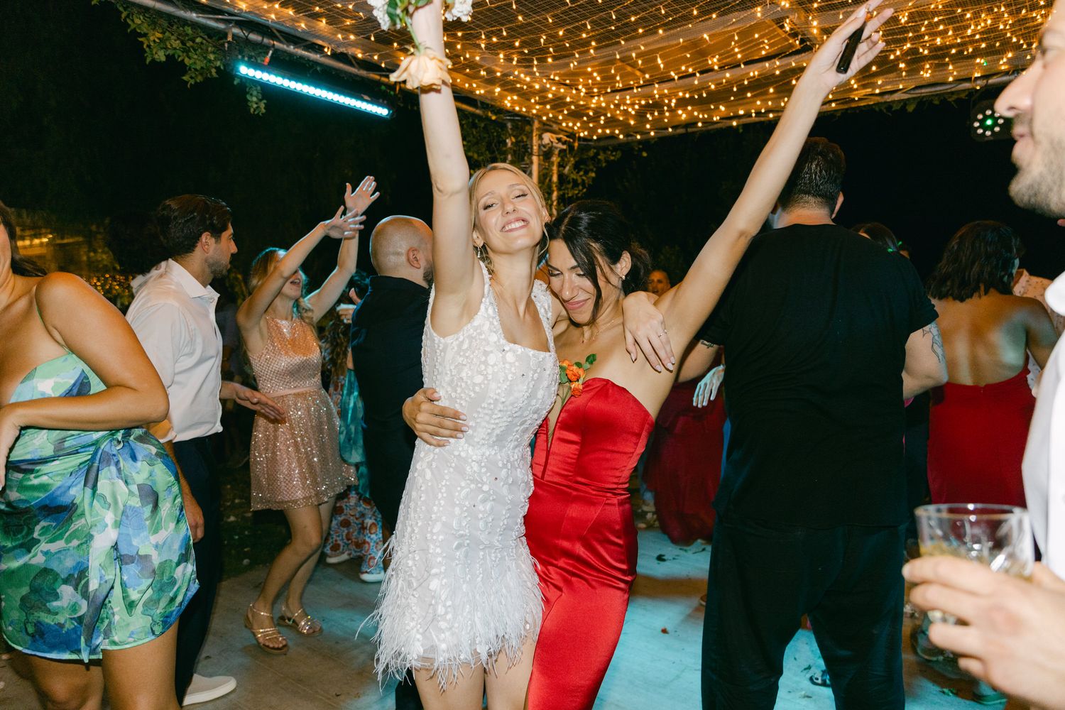 Dancers celebrating on a festive dance floor under twinkling string lights at an evening party.