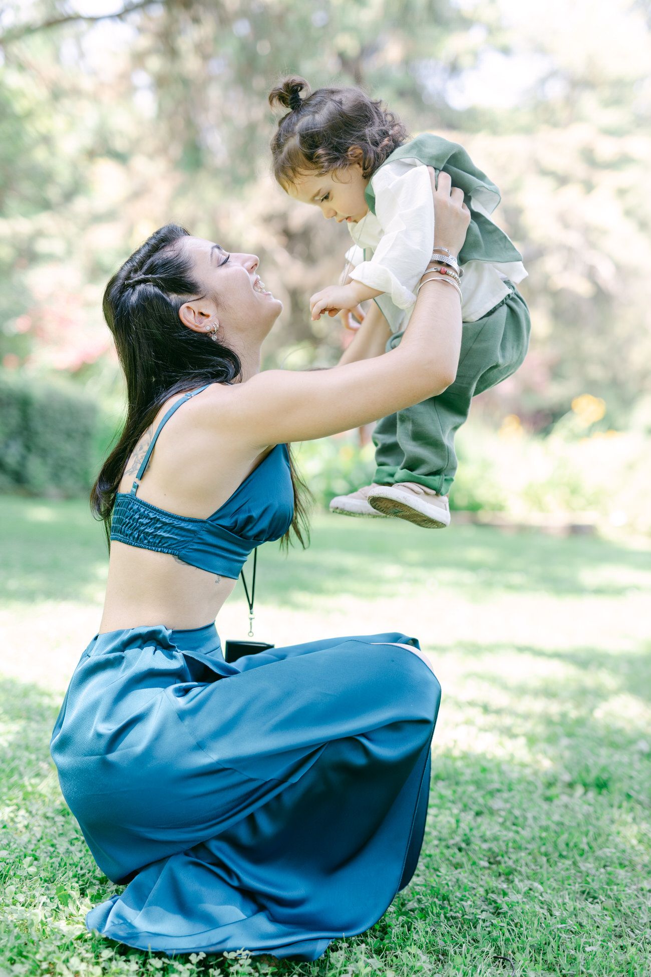 A joyful moment captured outdoors showing playful interaction in a blue outfit on green grass in soft natural lighting.