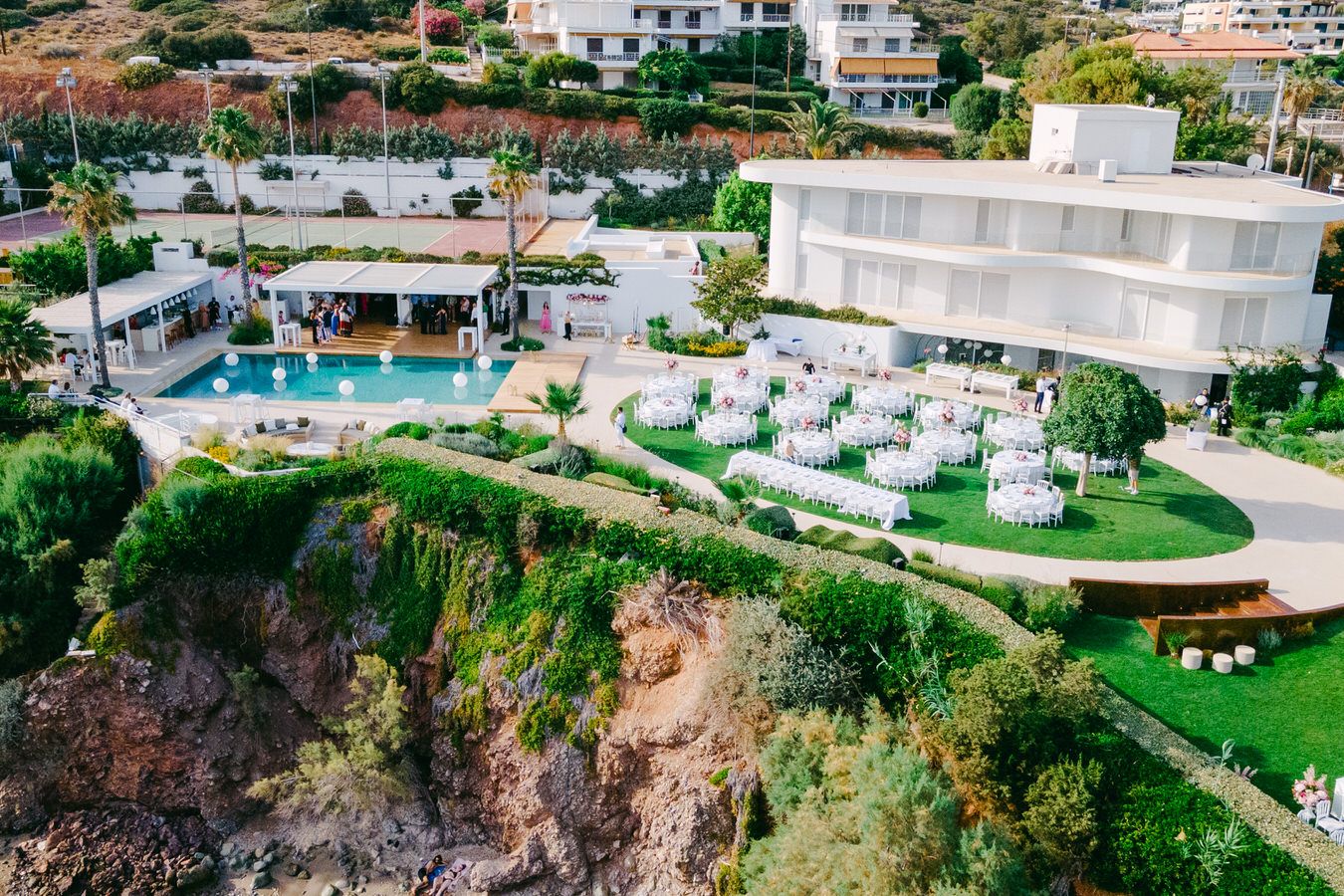 Luxury resort venue with cliffside pool and outdoor seating area overlooking the ocean on a sunny day.