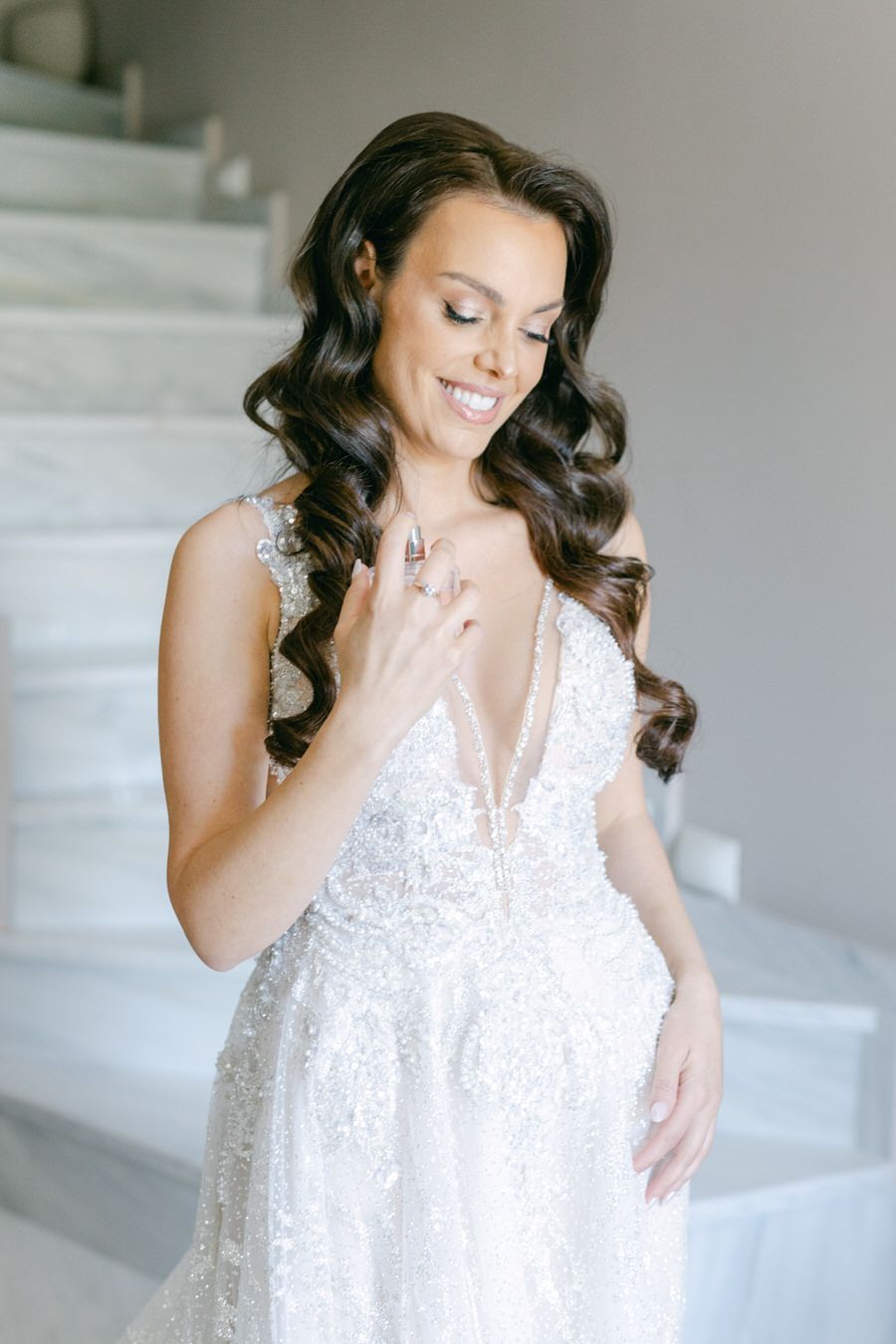 Radiant bride in detailed lace wedding gown with flowing dark curls.