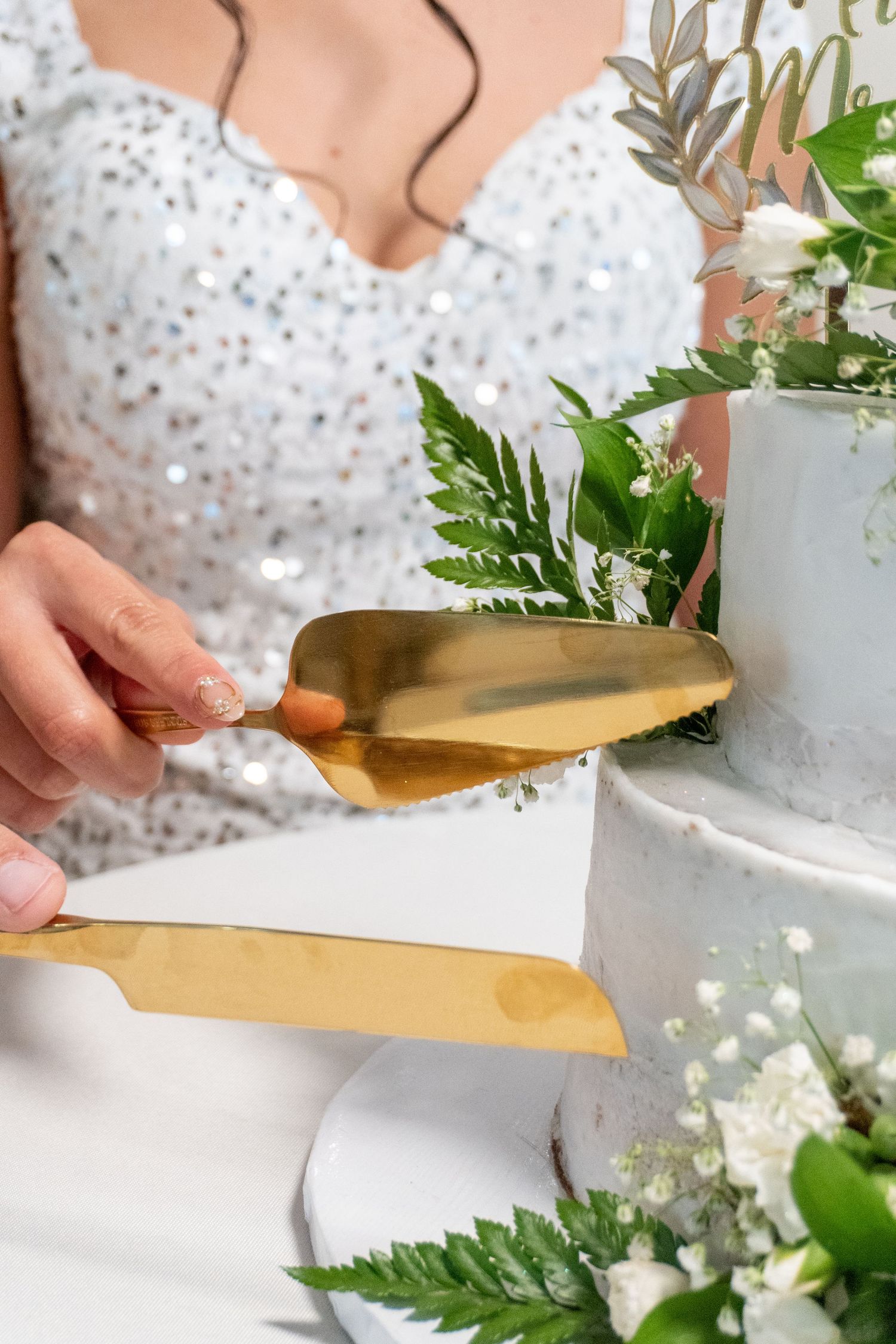 Close-up of hands opening a white wedding gift box with greenery and floral decorations.