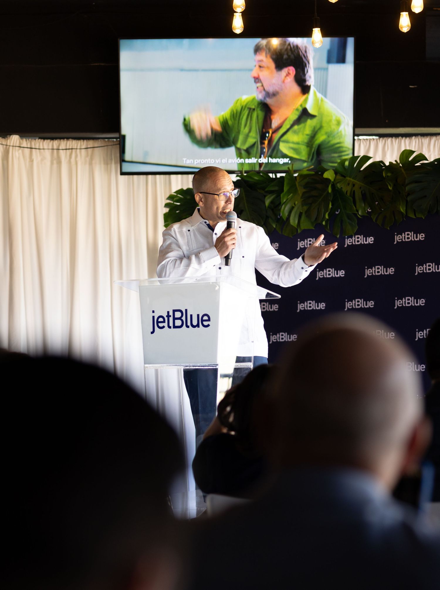 Corporate presentation event with JetBlue branding and audience silhouettes.
