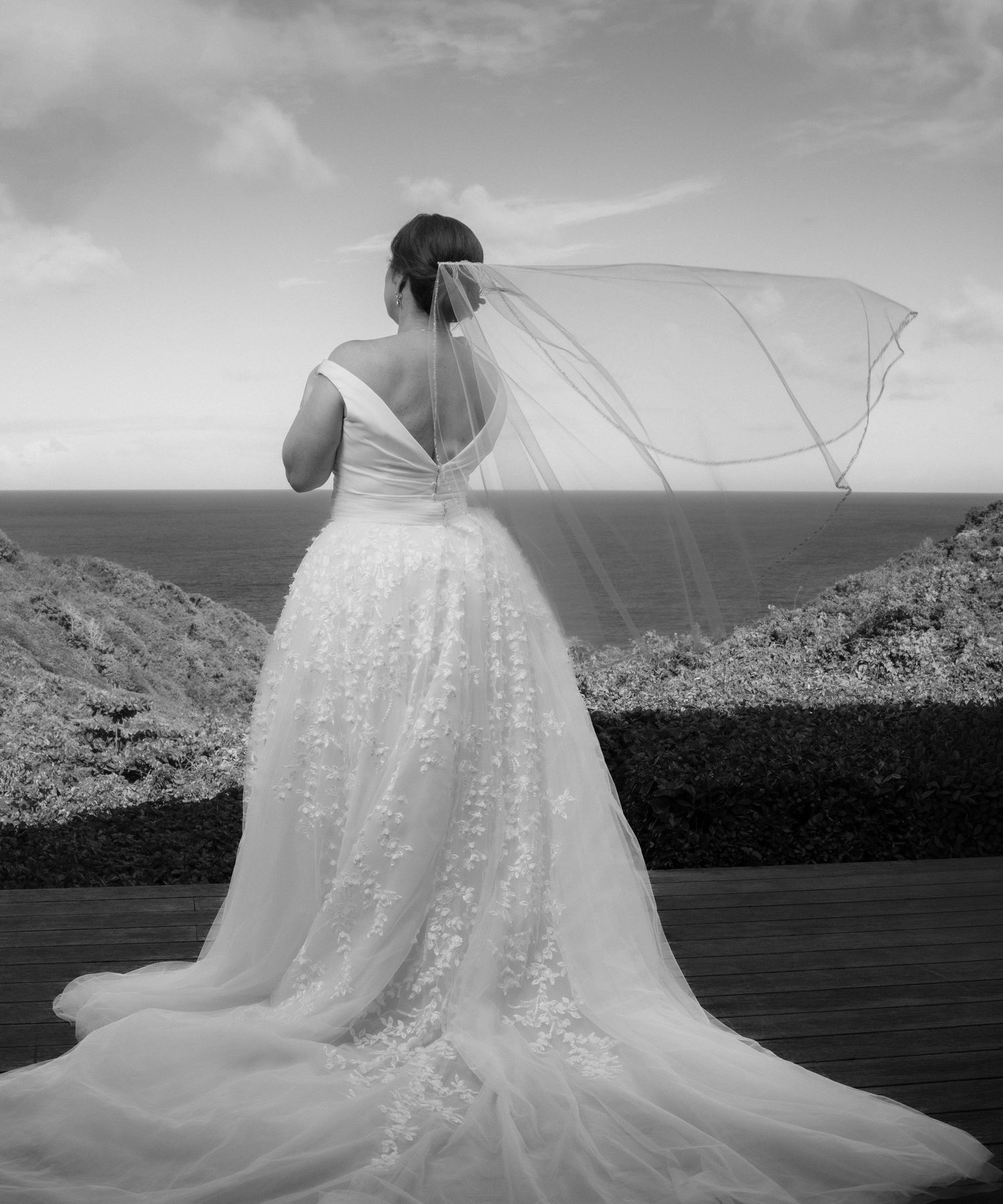 A flowing white wedding dress train spreads elegantly across a dramatic mountain landscape in black and white.