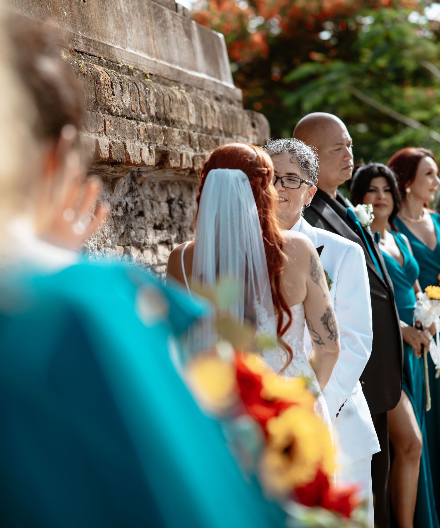 Wedding ceremony guests seated outdoors with colorful floral decorations.