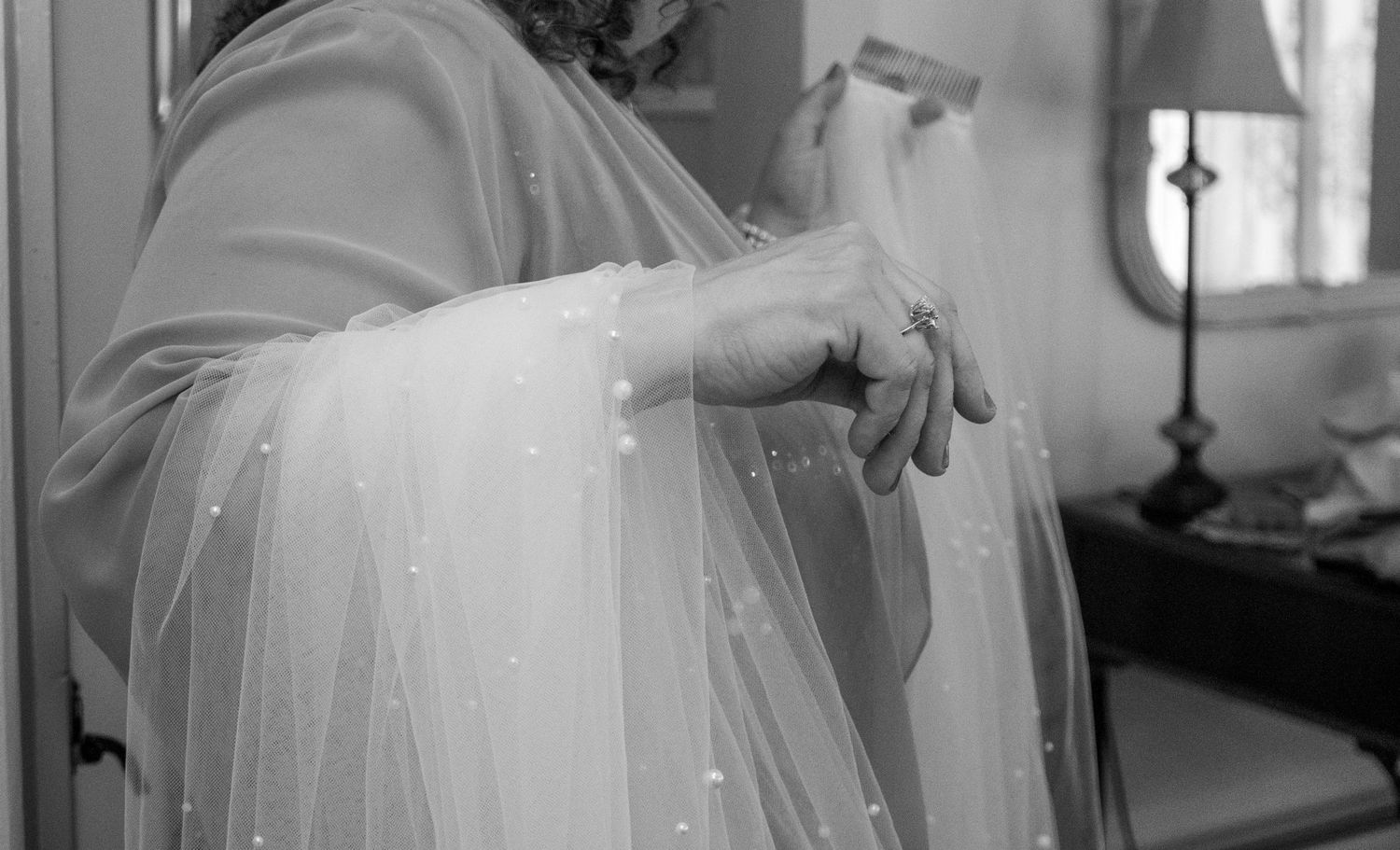 Elegant wedding preparation scene with flowing white veil in natural window light.