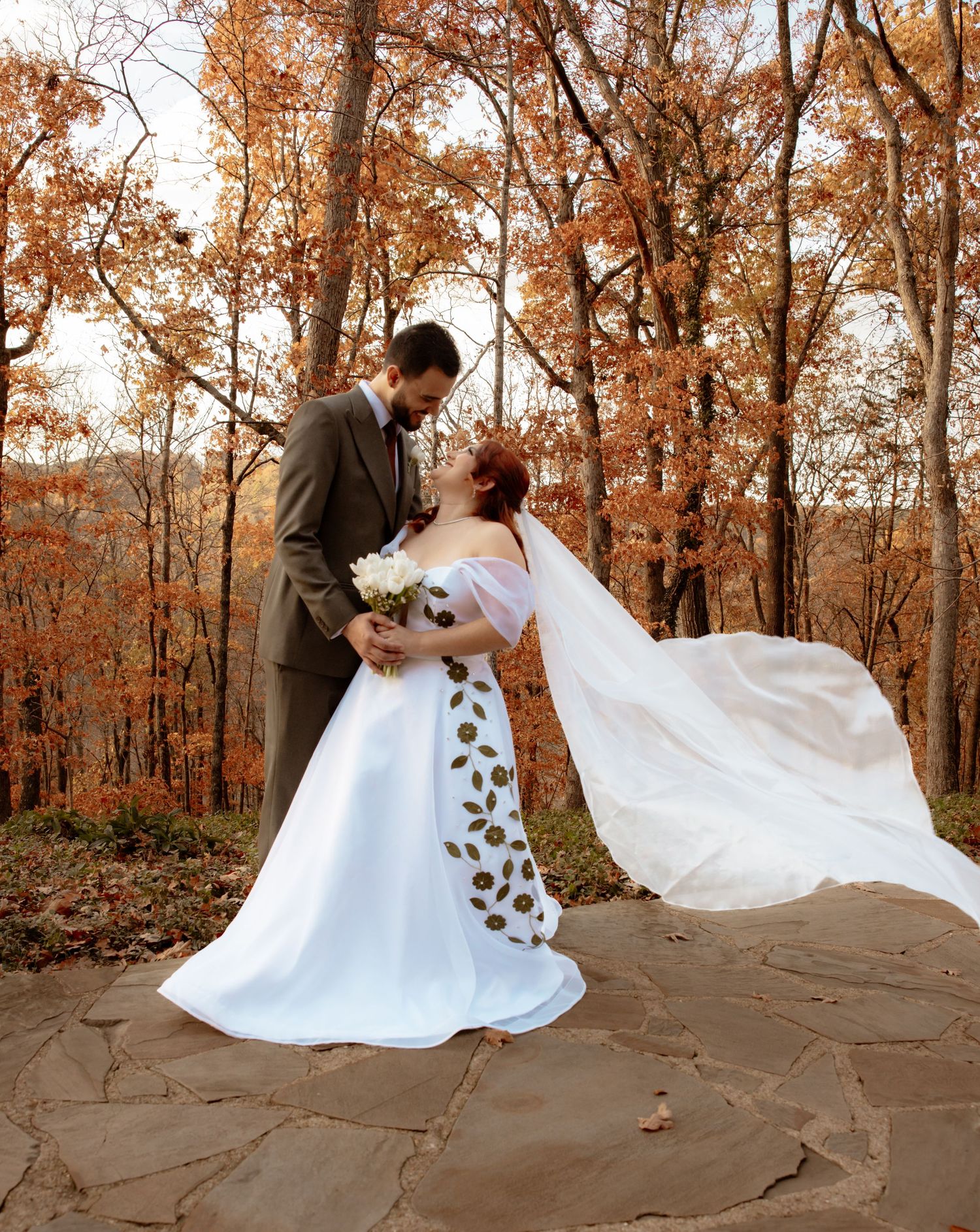 Wedding couple dancing and posing in autumn forest with fallen leaves.