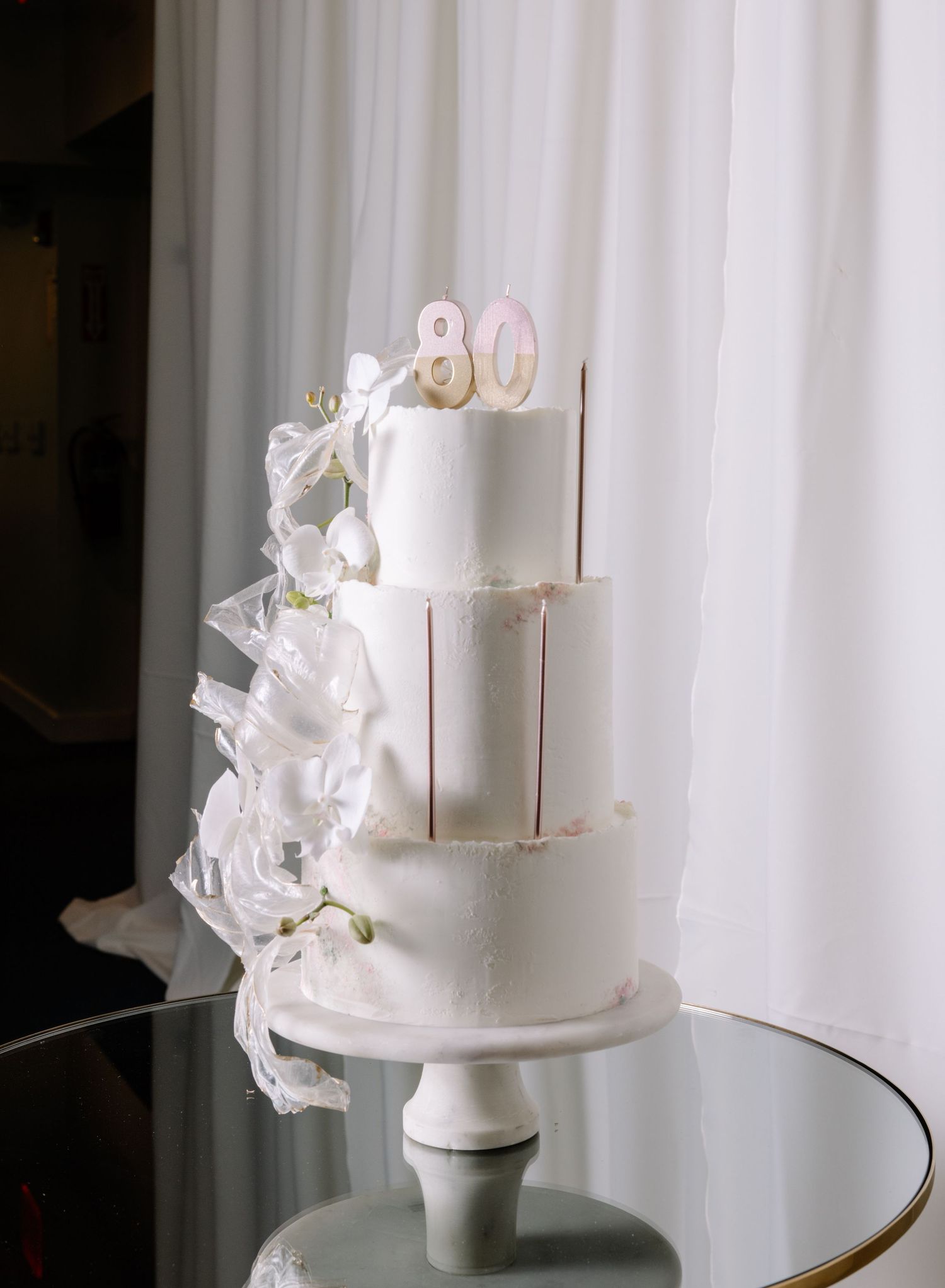 Elegant white birthday cake decorated with delicate sugar flowers.