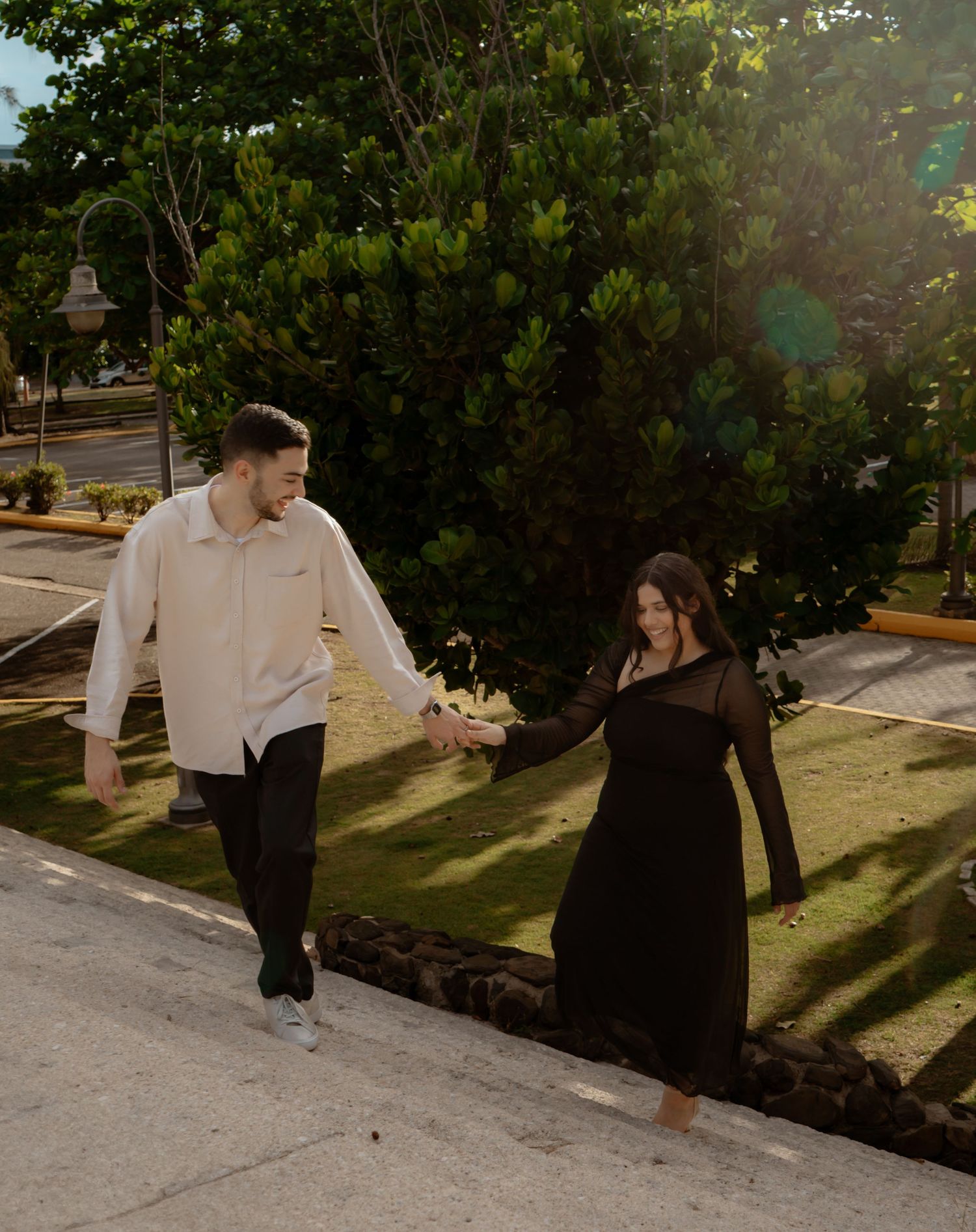 Playful interaction between two people in a garden setting with dramatic shadows.