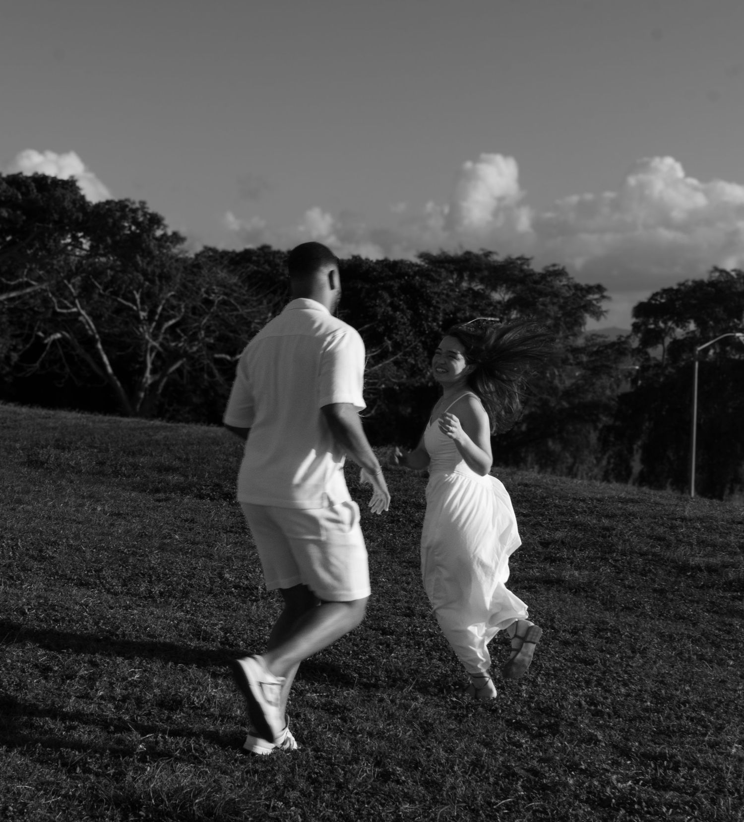 Couple walking up a grassy hill in black and white photography.