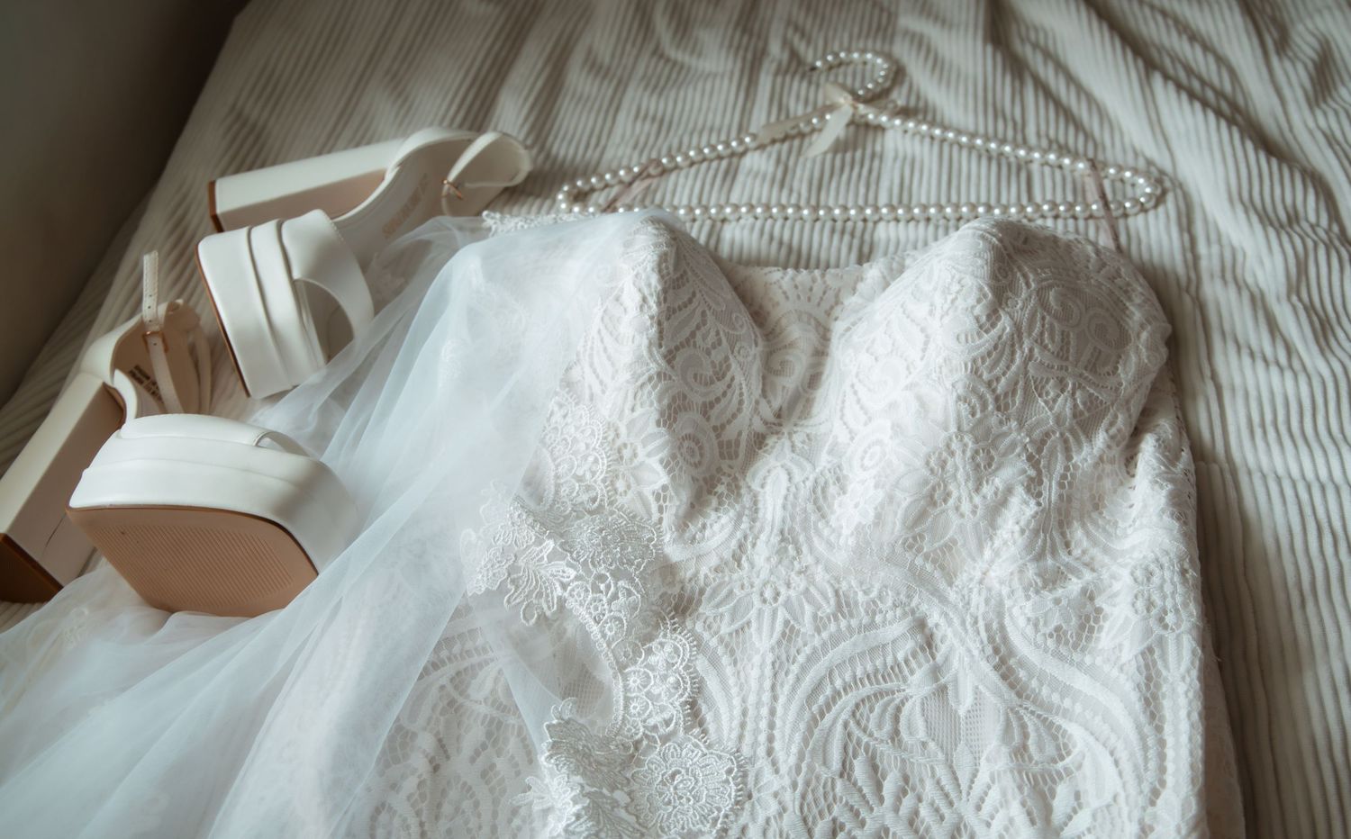 Close-up details of delicate white lace and embroidered fabric with intricate floral patterns and textures.