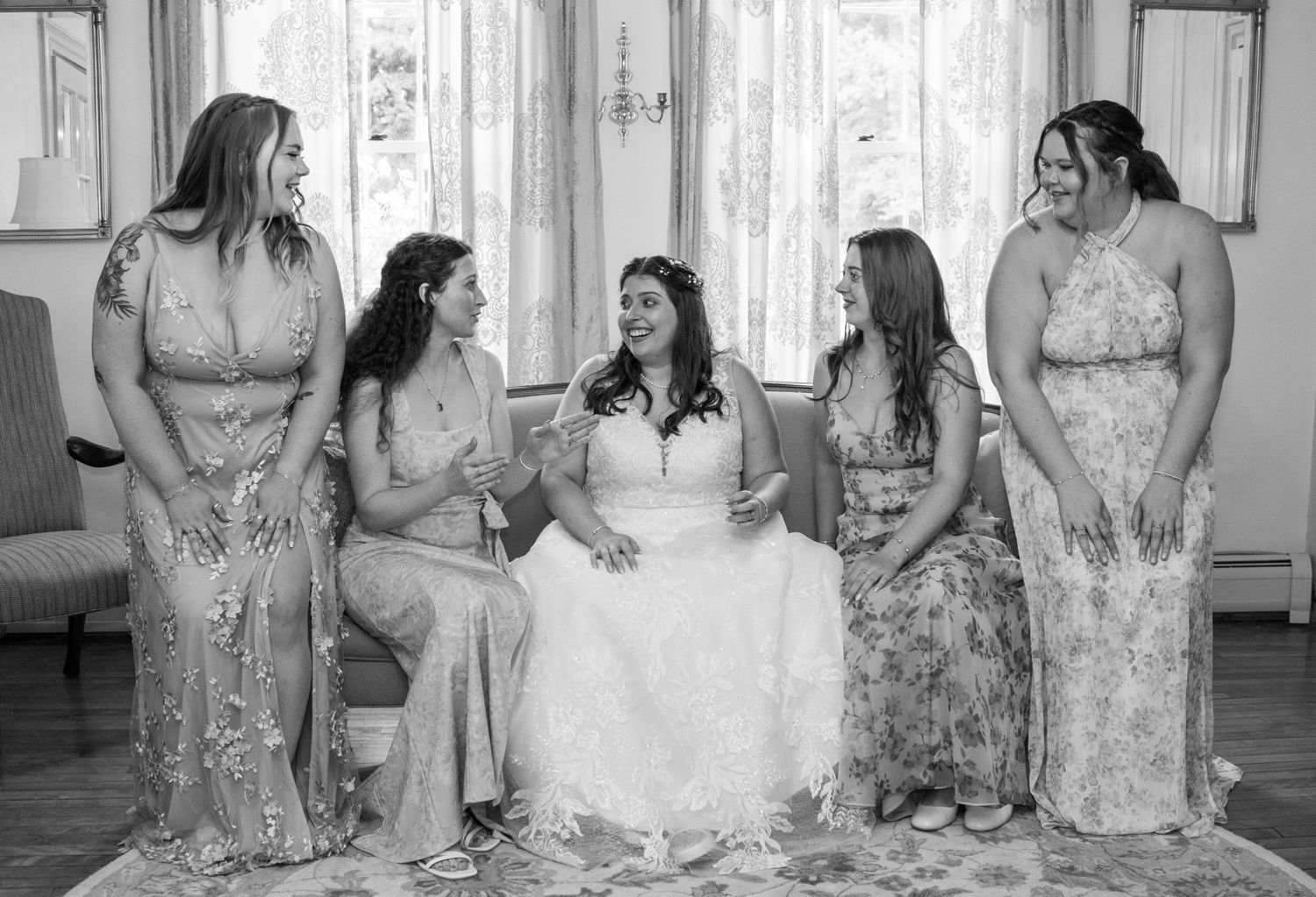 Bridesmaids in matching floral dresses sharing candid moments with bride.