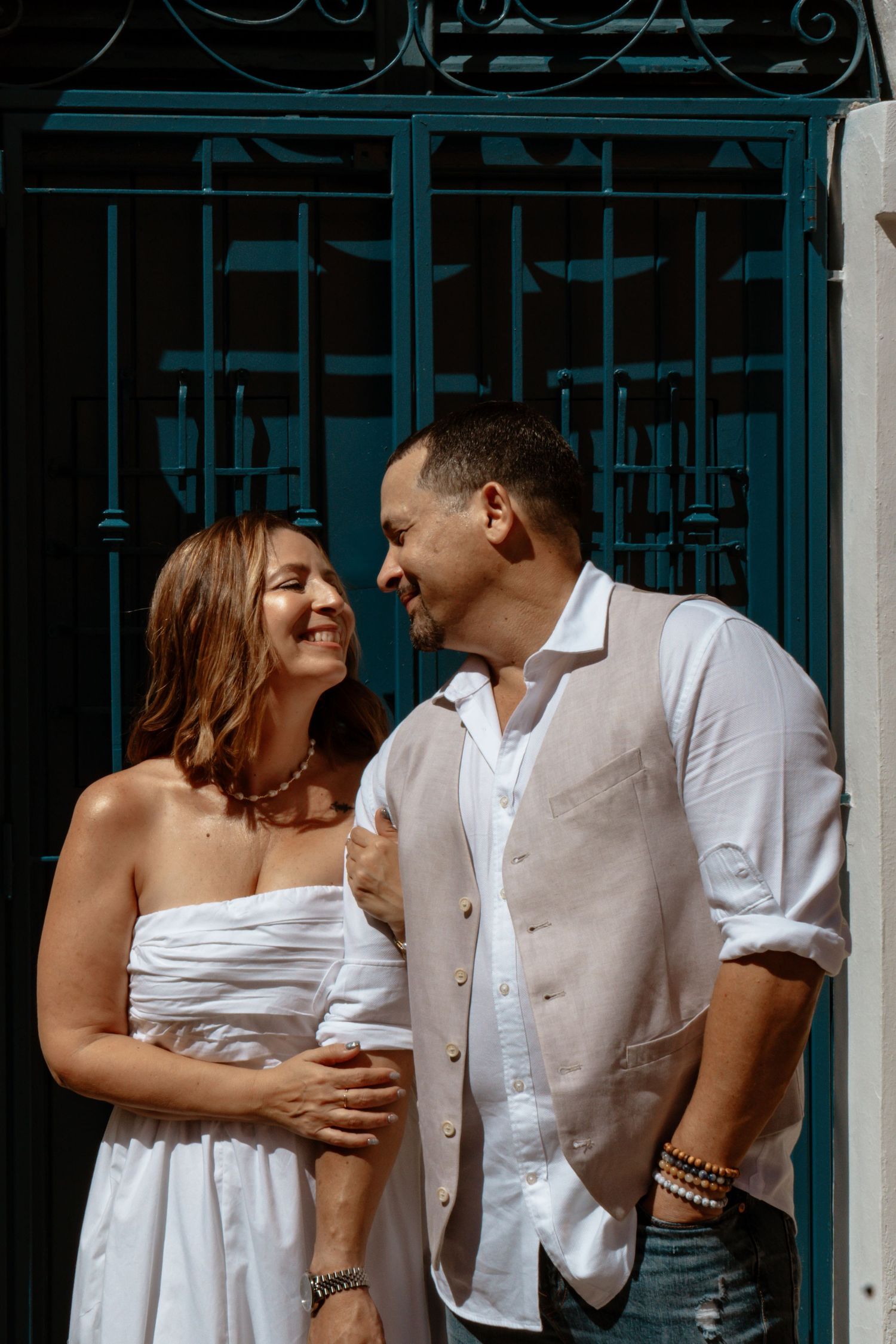 Intimate moment shared against ornate blue metal gates.