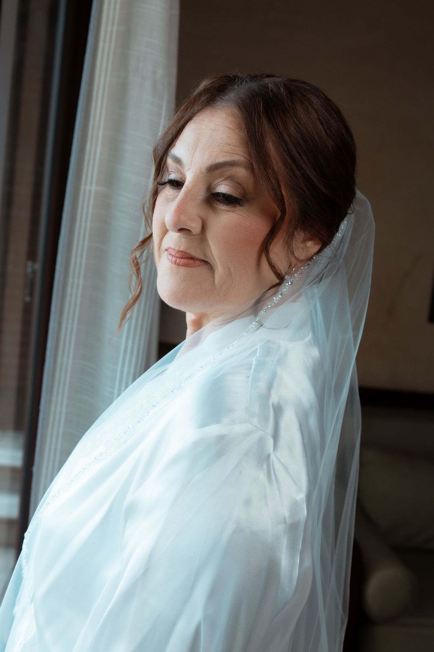 A bride in a white veil poses near a window in a series of candid shots.