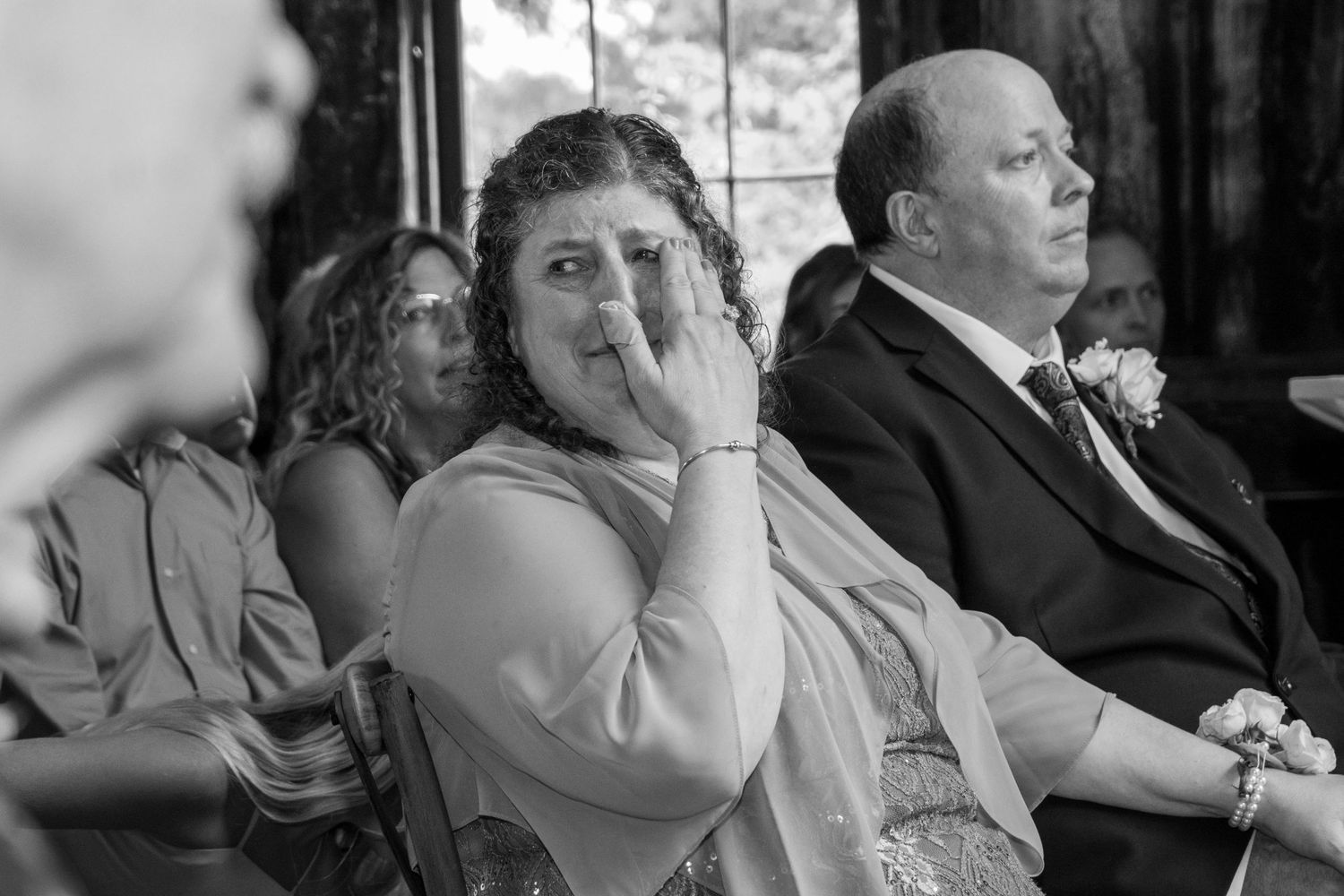 Wedding guests react emotionally during a ceremony in a series of candid black and white photographs.