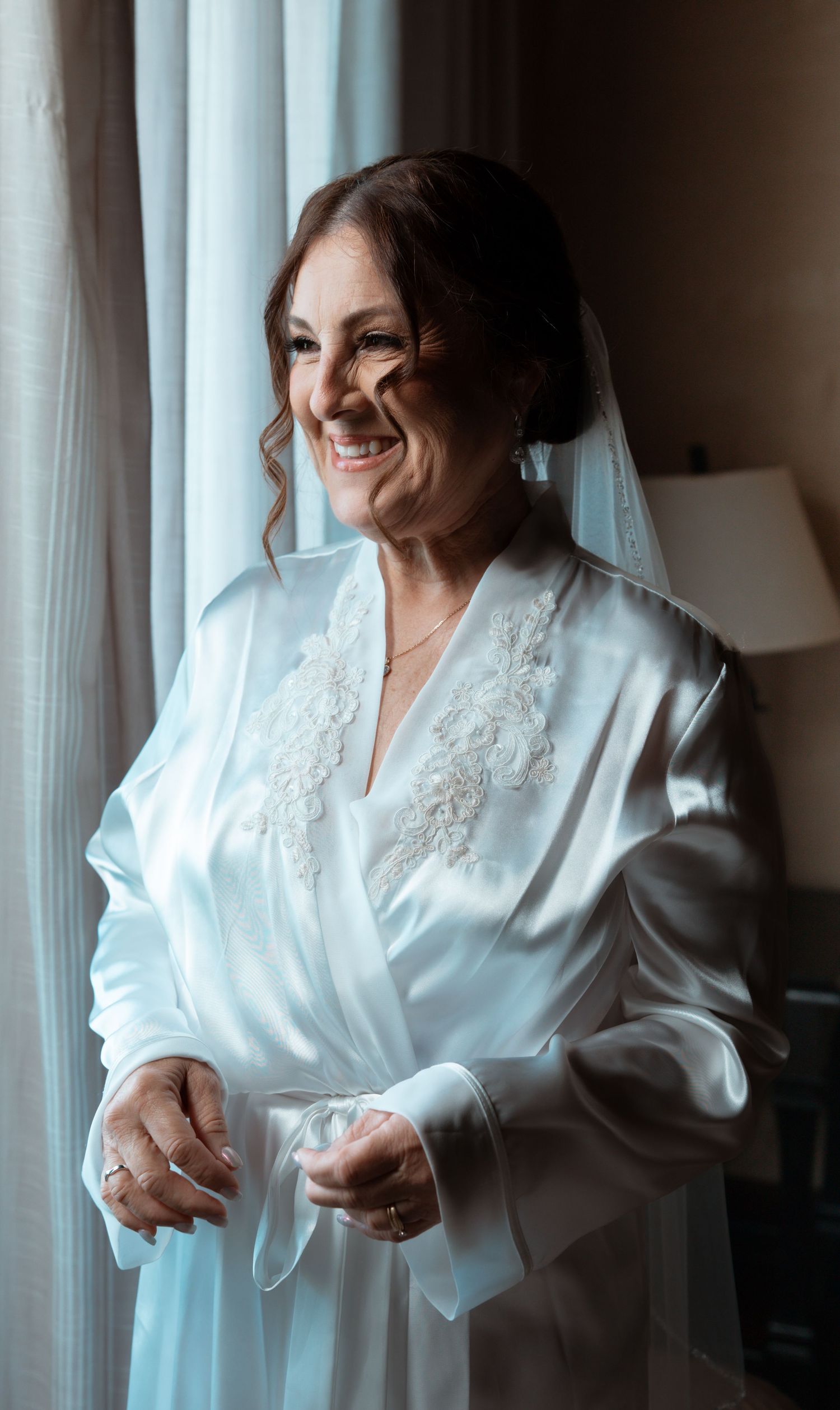 A series of four photos showing someone in a white satin robe getting ready by a window with natural light.