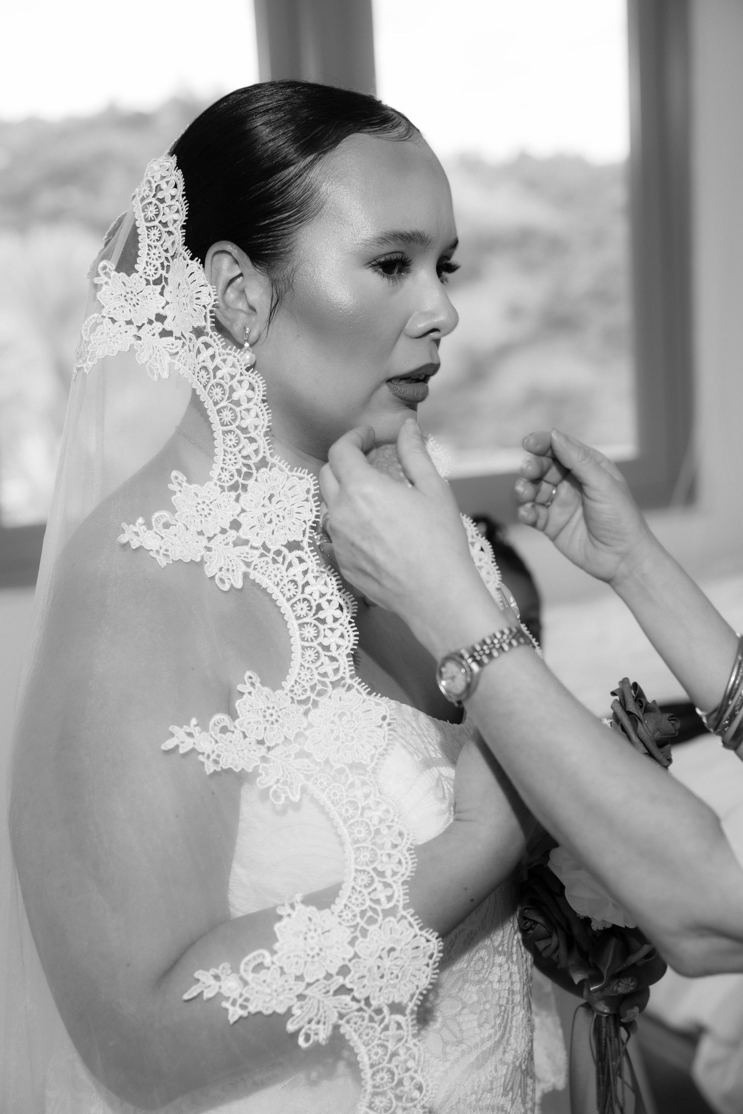 Black and white wedding photo series showing a bride putting on delicate lace accessories.