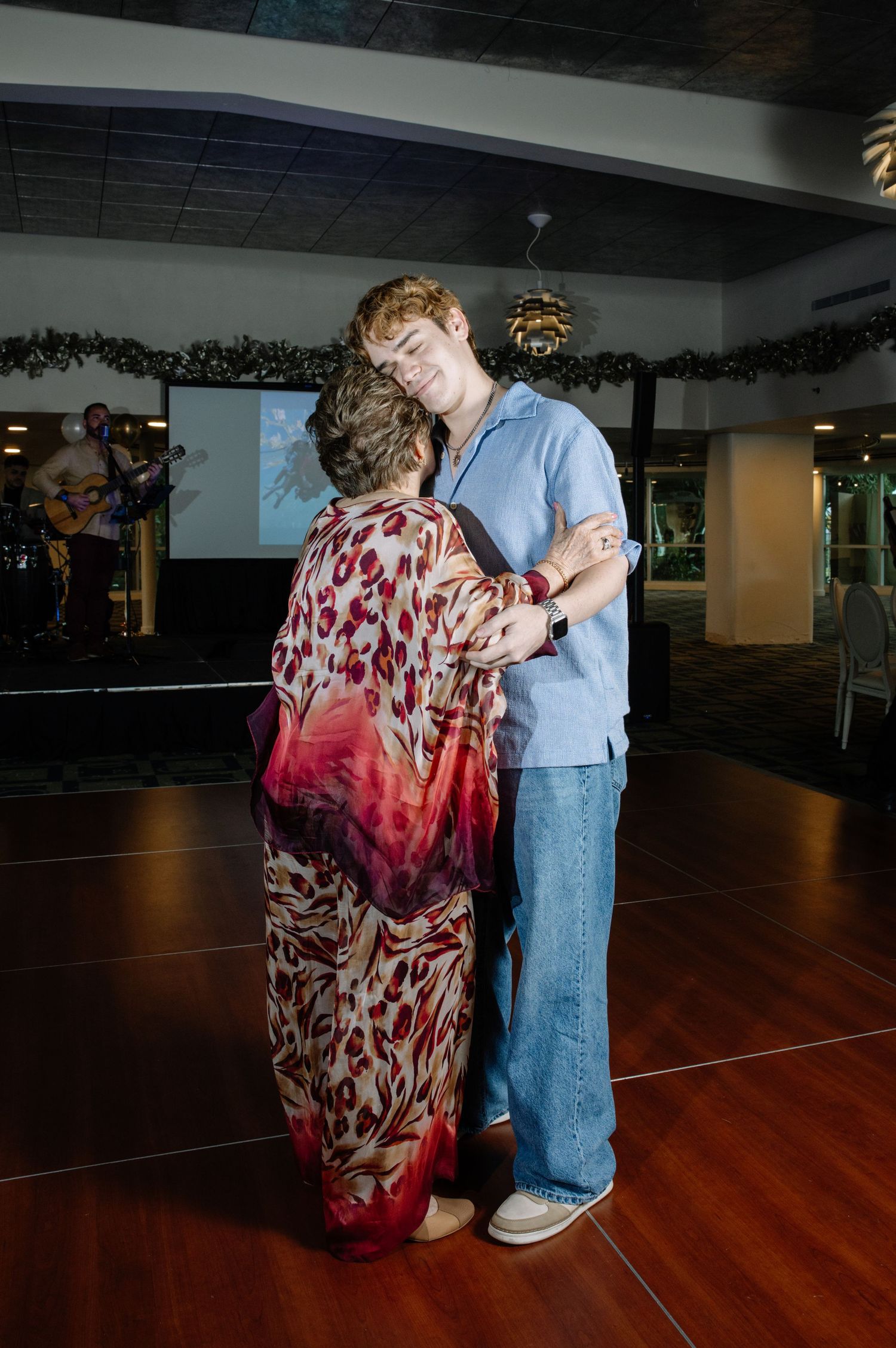 Two people dancing together on wooden floor in dimly lit room.
