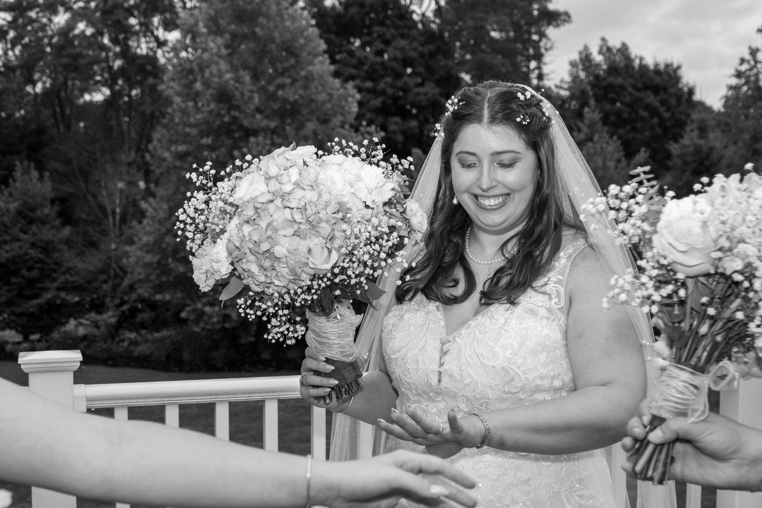 A wedding couple poses outdoors with delicate white baby's breath bouquets against a natural backdrop.