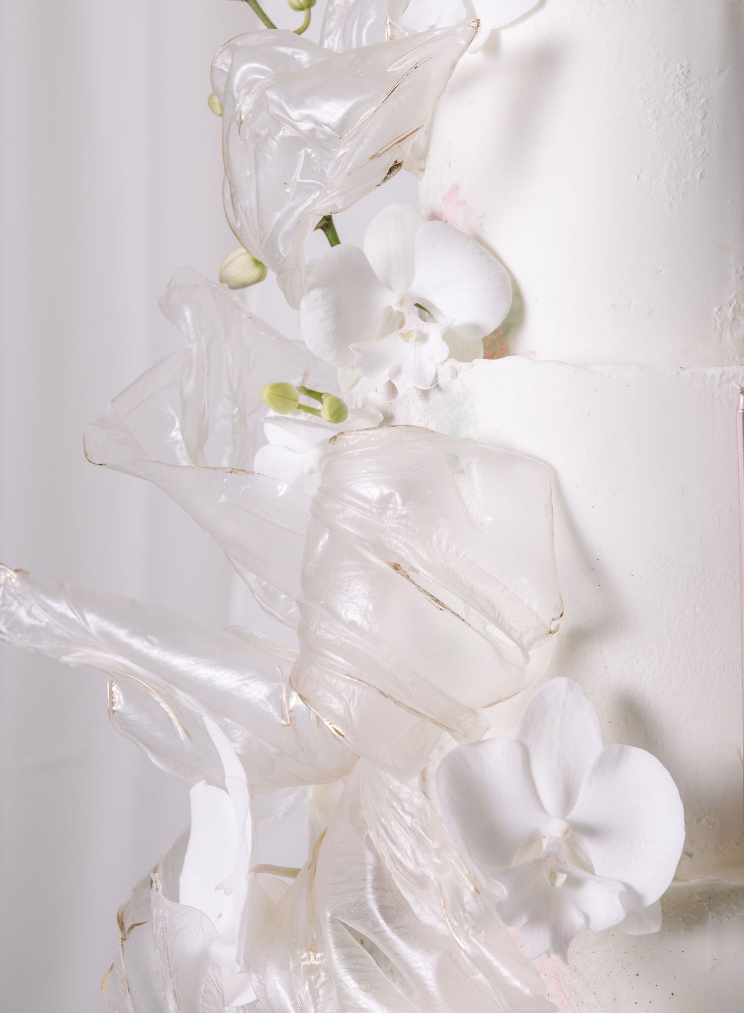 Abstract white textured tiered birthday cake with delicate floral elements.