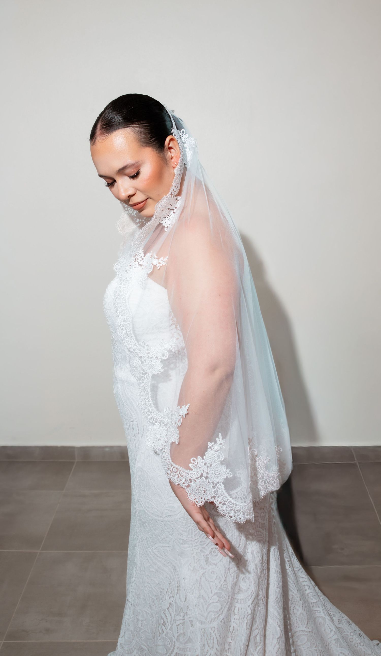 A bride wearing a white lace wedding gown and veil poses gracefully in a series of artistic bridal portraits.