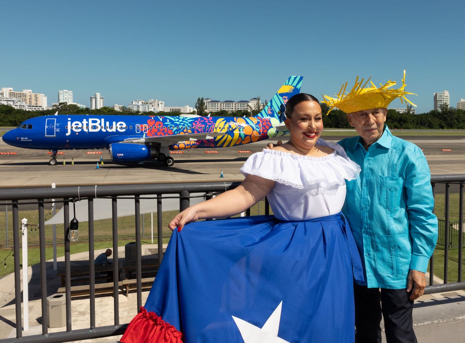 People holding Puerto Rican flag in front of JetBlue aircraft.