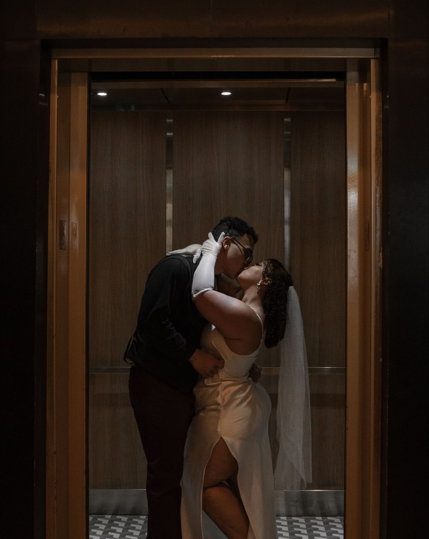 A romantic moment between newlyweds in an elegant wood-paneled elevator.