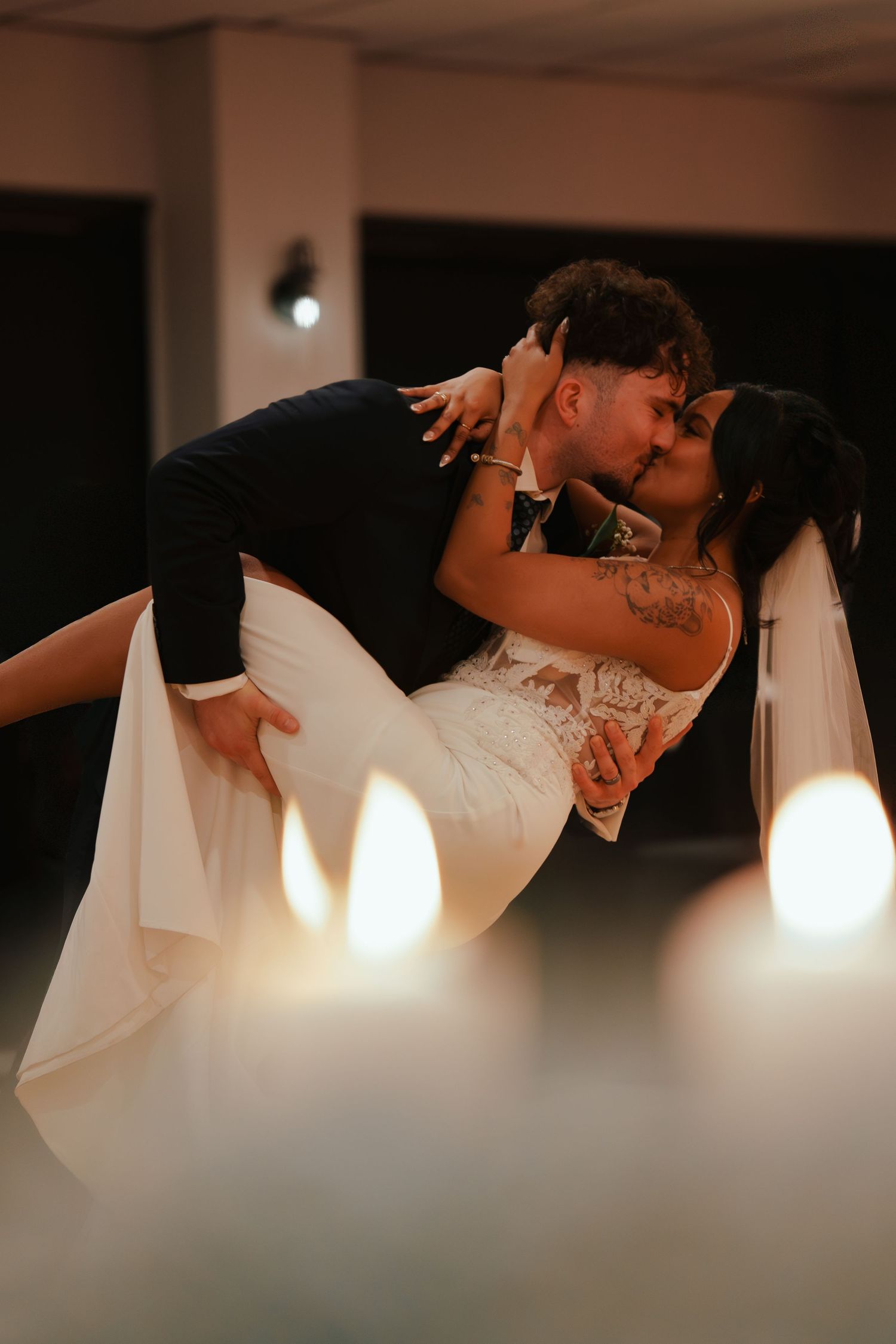 A dramatic dance dip captured from above, showing the flowing movement of a white wedding dress against a dark floor.