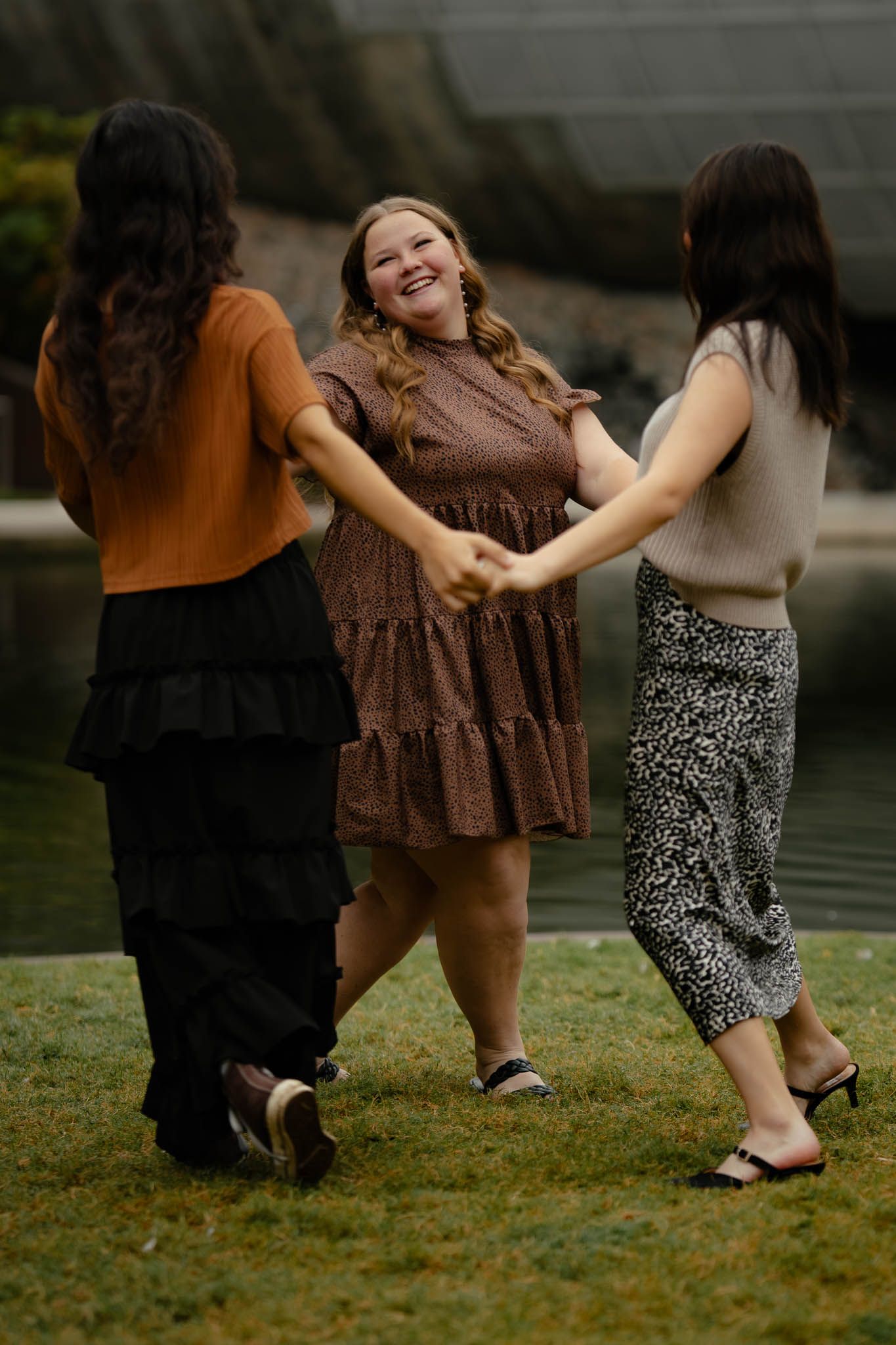 A group dancing and laughing together on a grassy lawn.