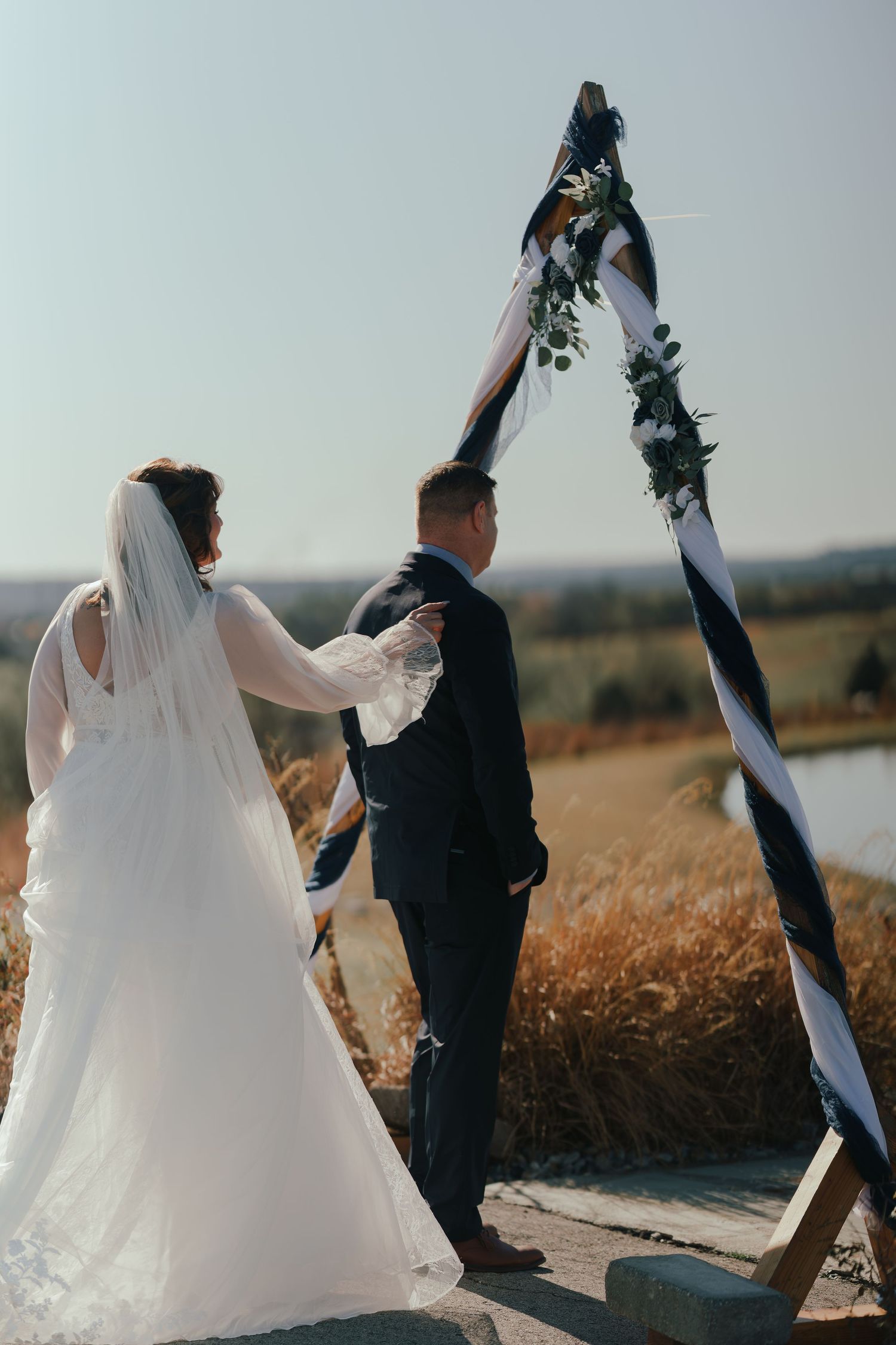 A romantic wedding couple walks through a golden wheat field at sunset, their silhouettes creating a dreamy scene.