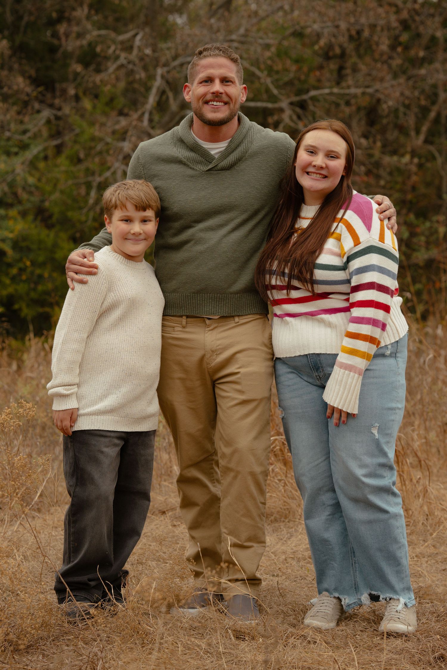 Family of four posing together in coordinated outfits during fall photo session.
