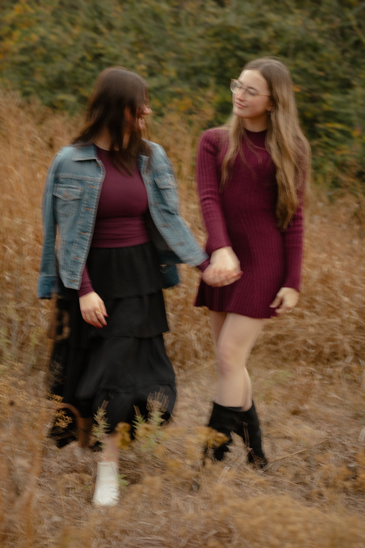 Two people in casual outfits dancing and having fun in a field.