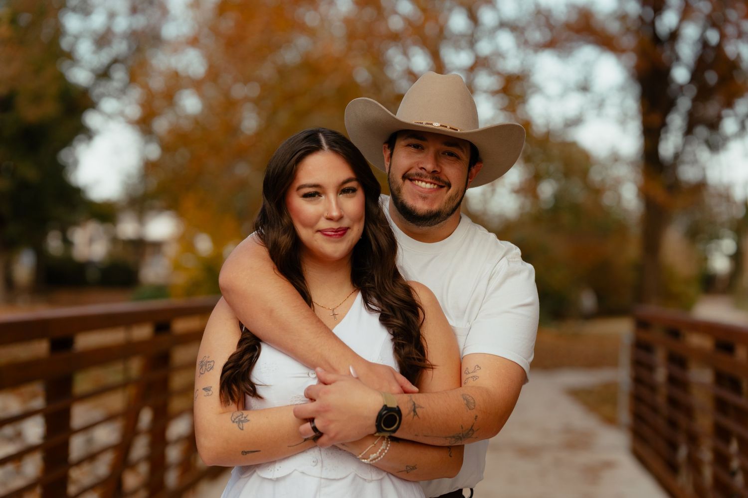 Couple embracing on wooden bridge during autumn sunset.