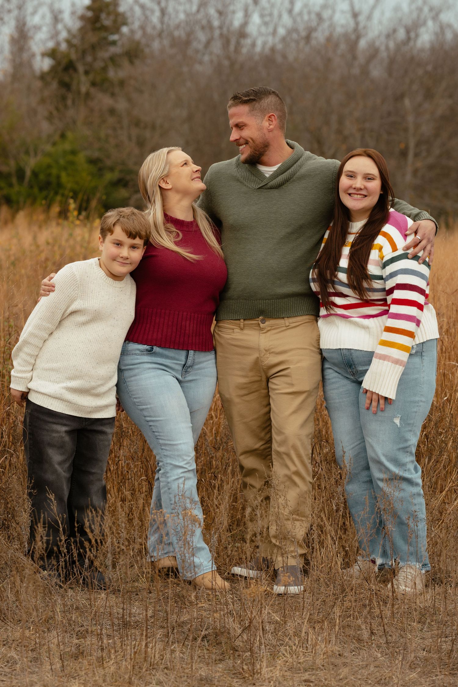 Family members walk together through tall grass in a natural outdoor setting during fall.
