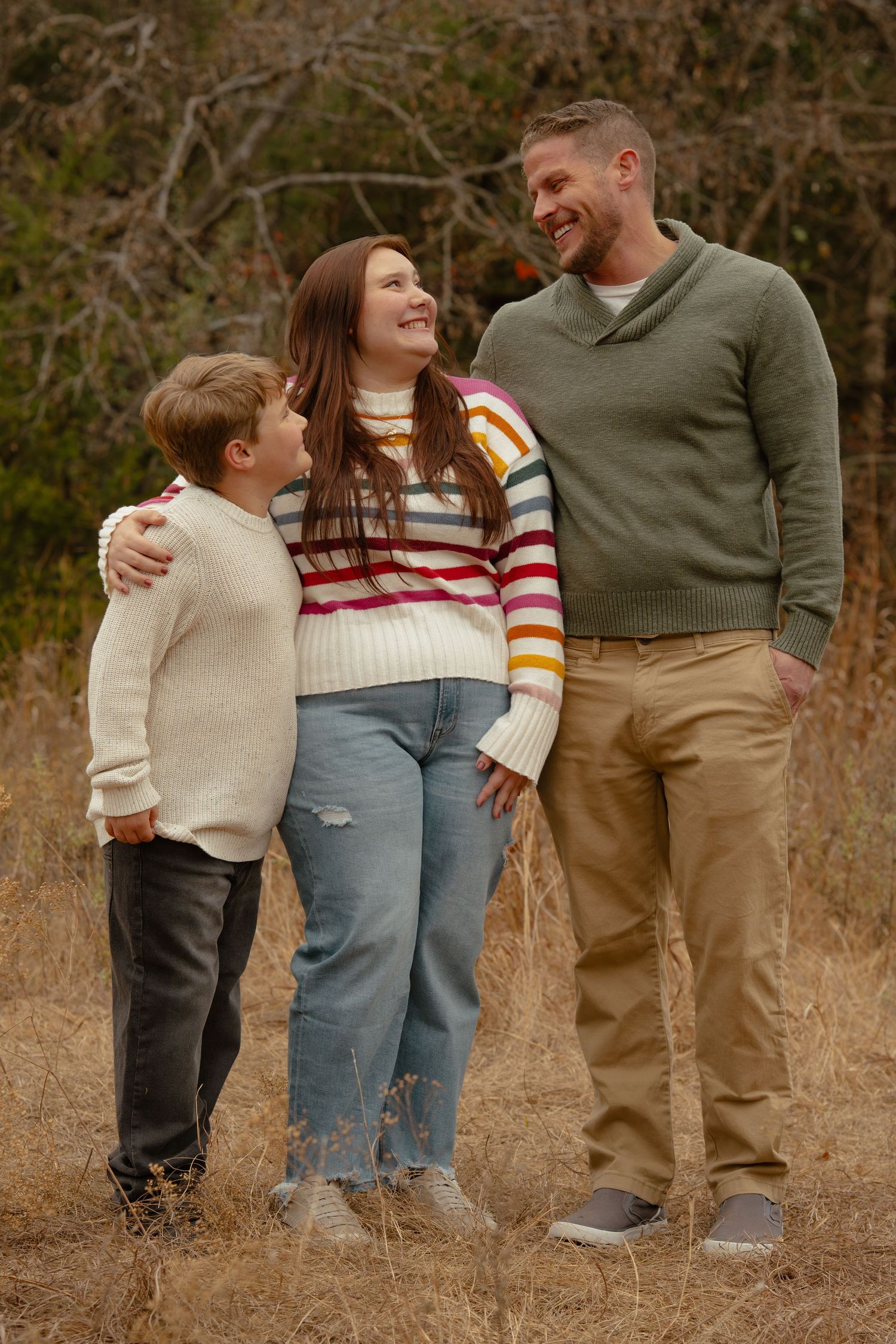 Family enjoying a playful outdoor photo session in casual fall attire against a natural backdrop.