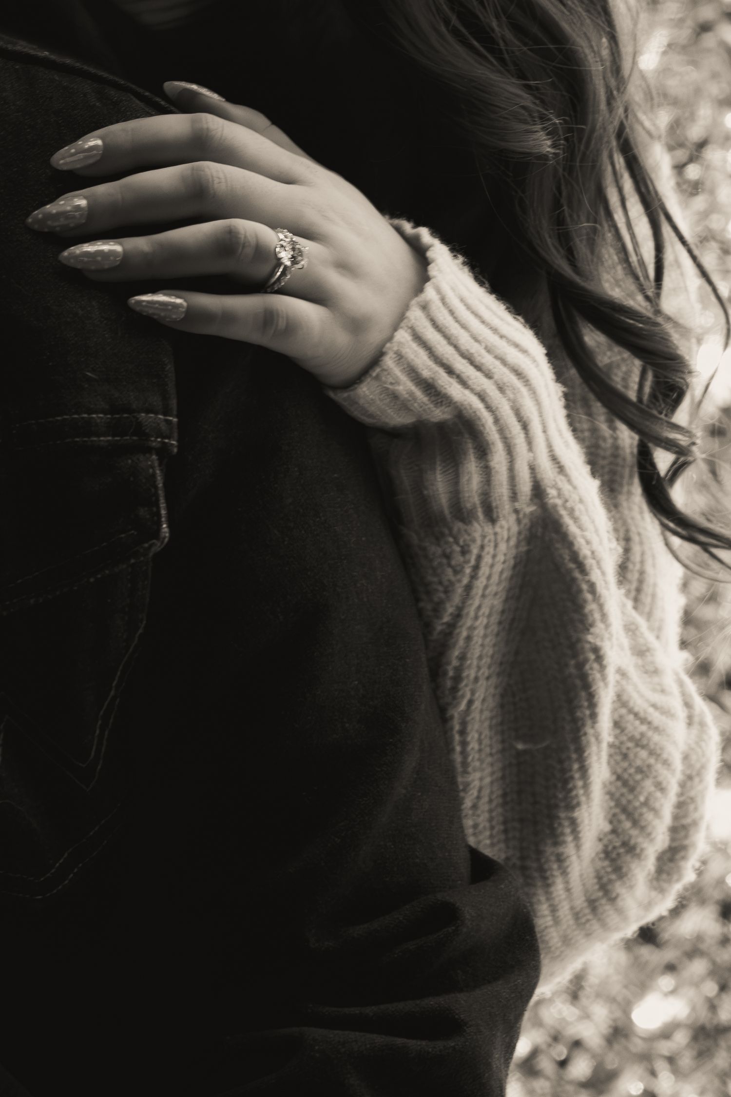 Black and white detail of hands with ring against knit sweater.